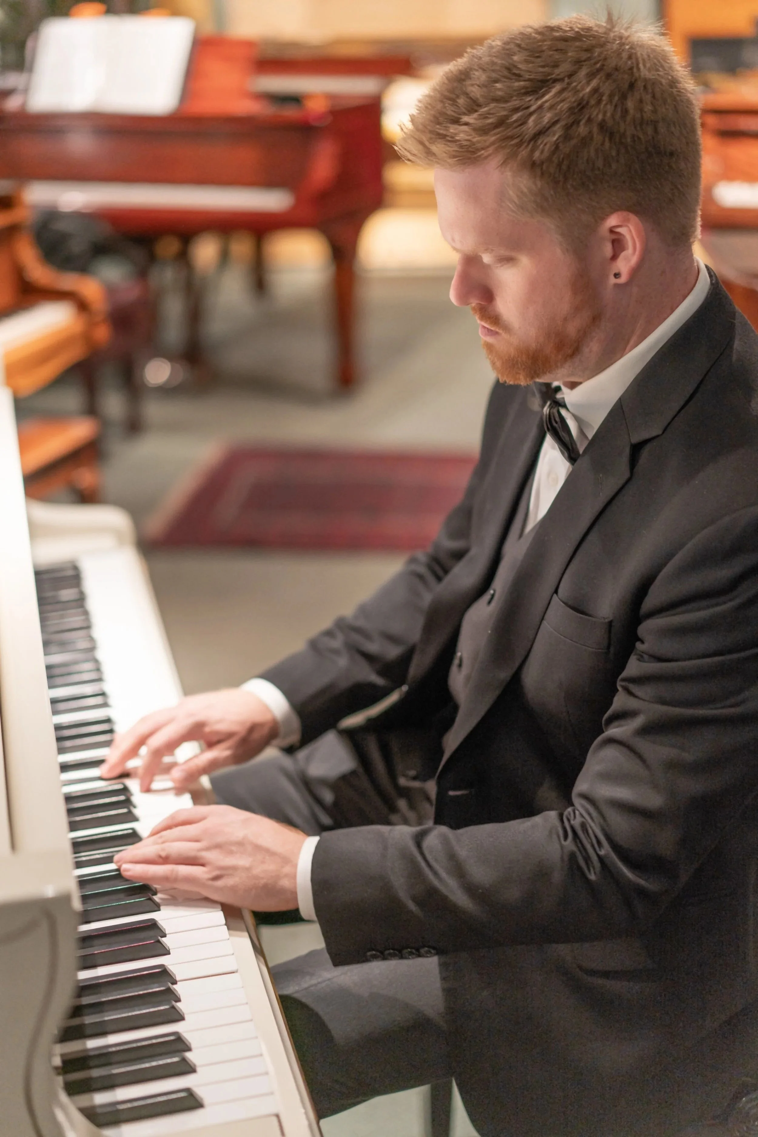 Pianist and piano teacher John Metz playing a white grand piano