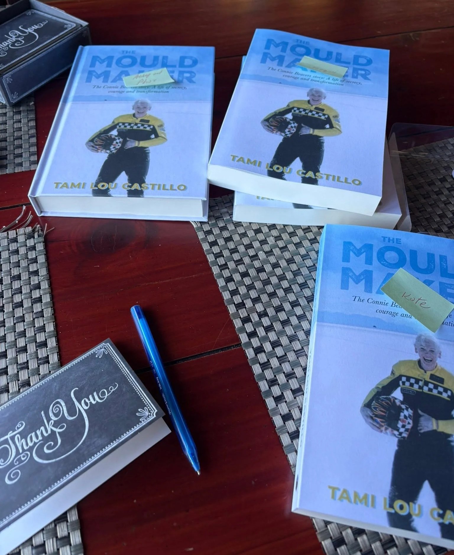 A few copies of The Mould Maker book by Tami Lou Castillo, with yello sticky notes on top and names written on each. Thanks you cards and a pen