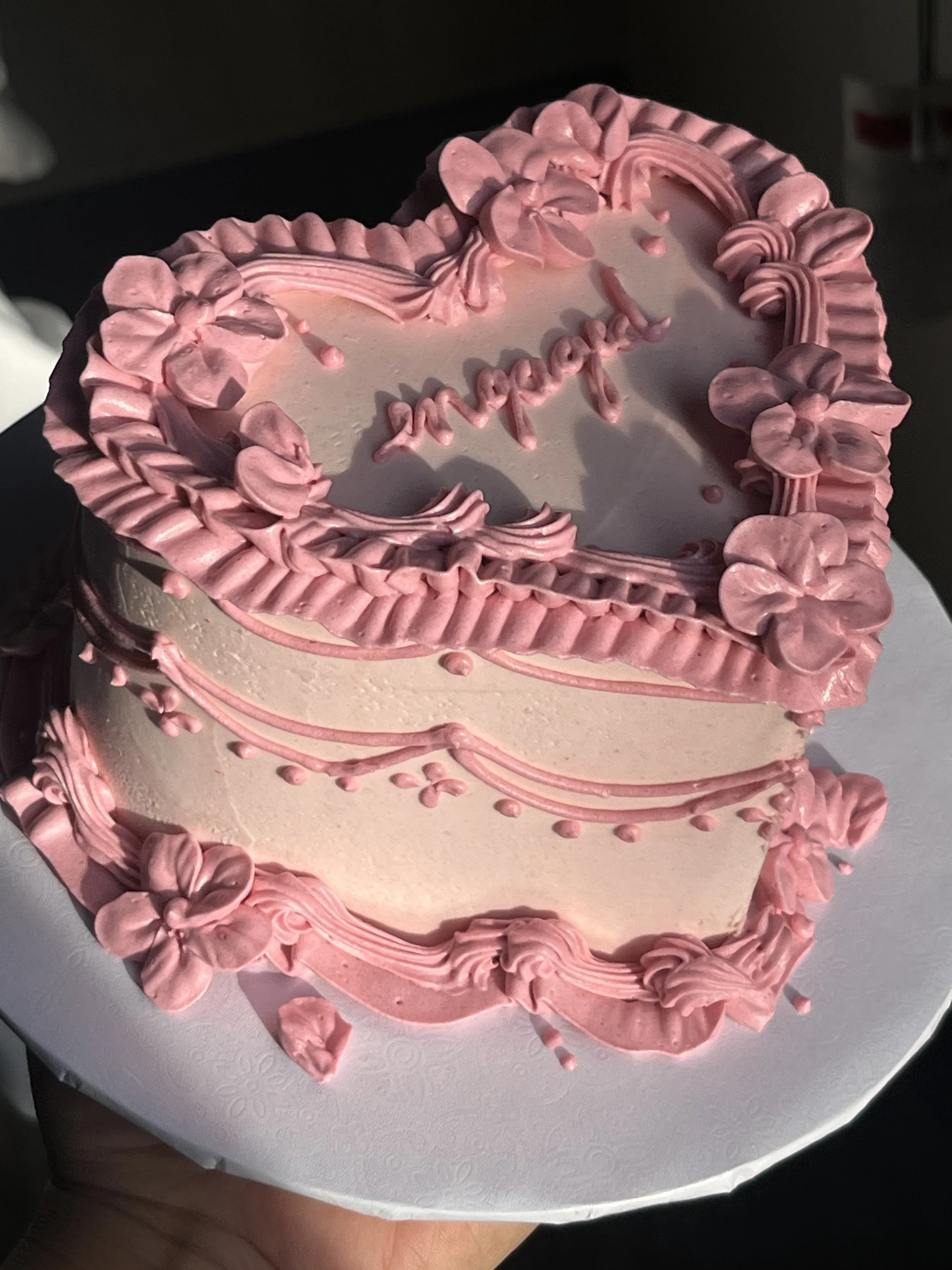 Heart-shaped cake decorated with pink and white frosting, with the message 'mommy' written on top in pink icing.