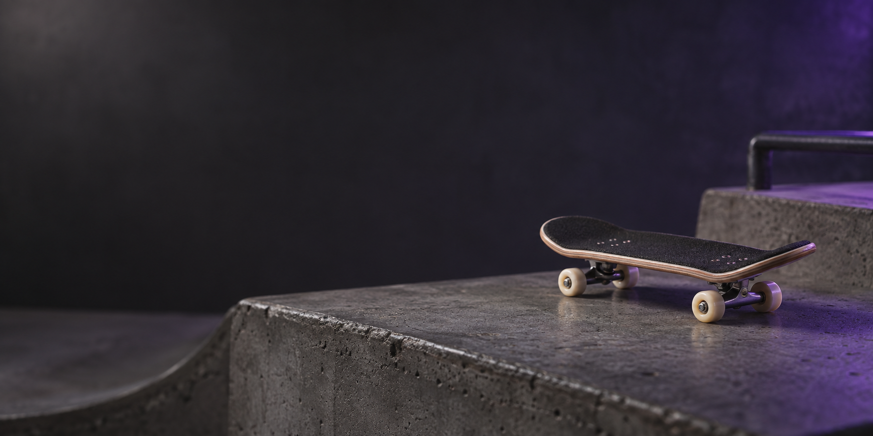 A black skateboard with white wheels resting on a concrete skatepark ledge inside a dark room with purple lighting.
