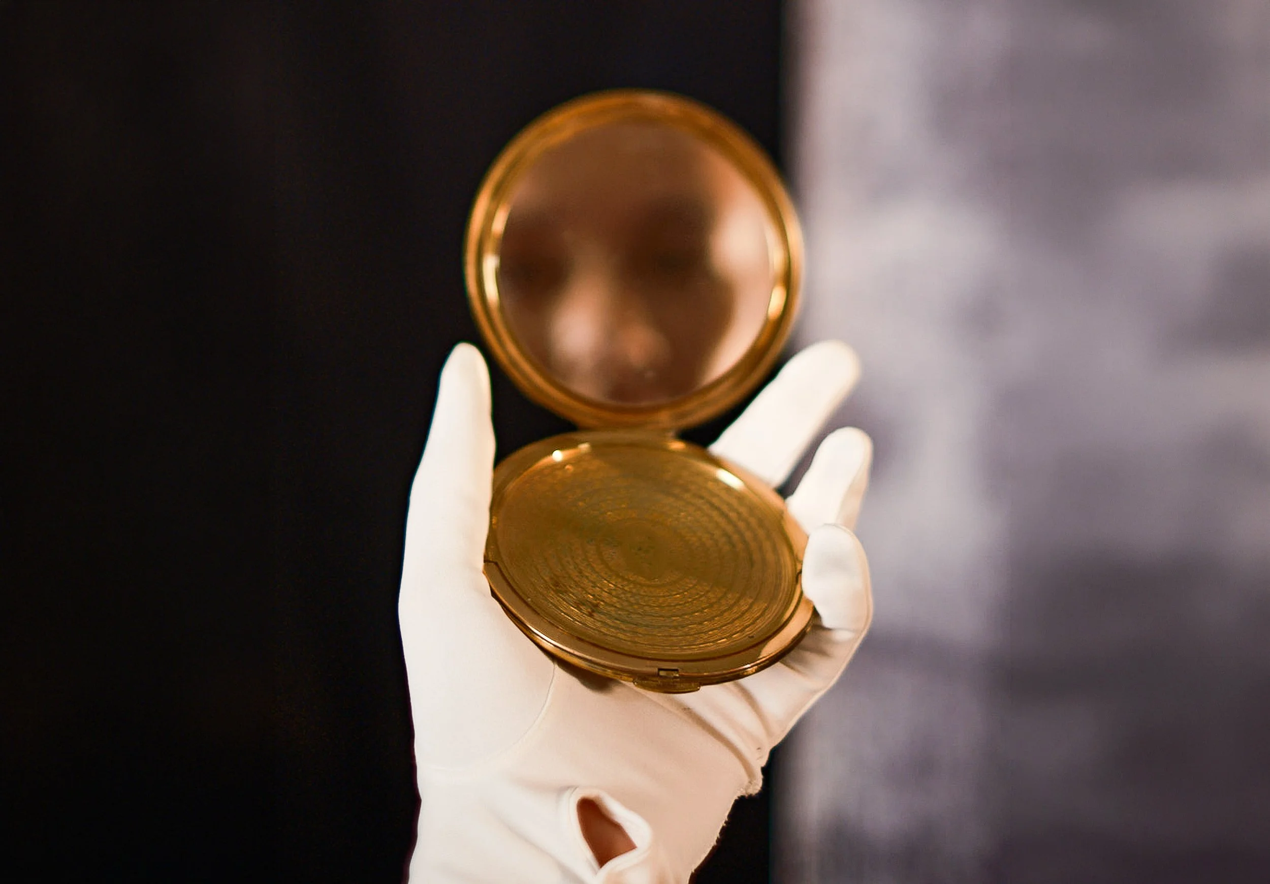Gloved hands holding an open antique gold pocket watch