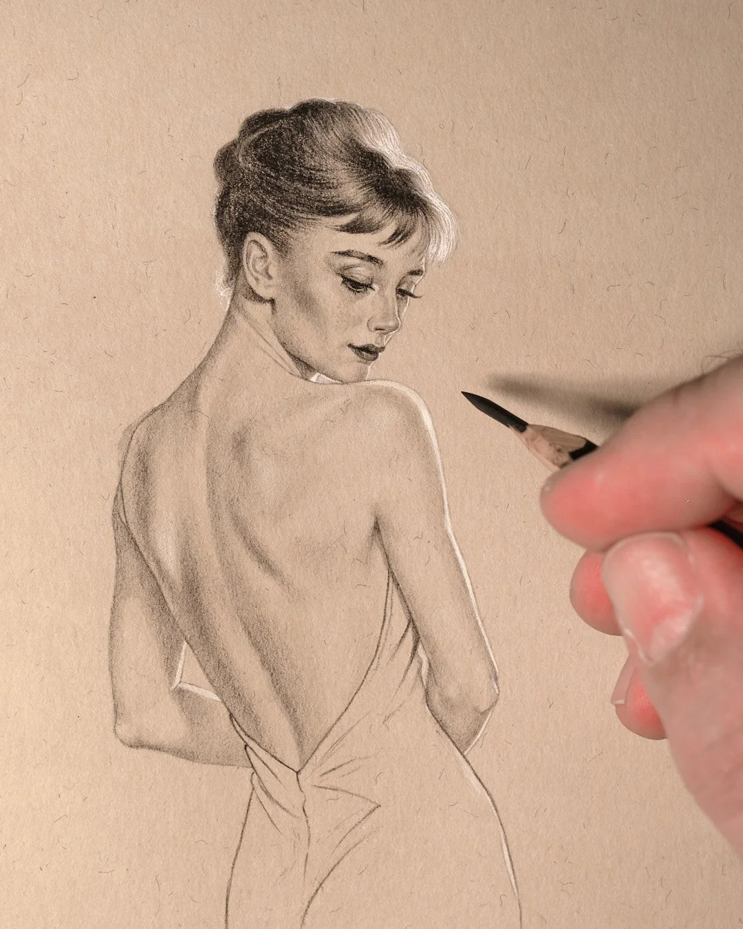 Artist’s hand shading a vintage-style pencil drawing of an elegant woman looking over her bare shoulder.
