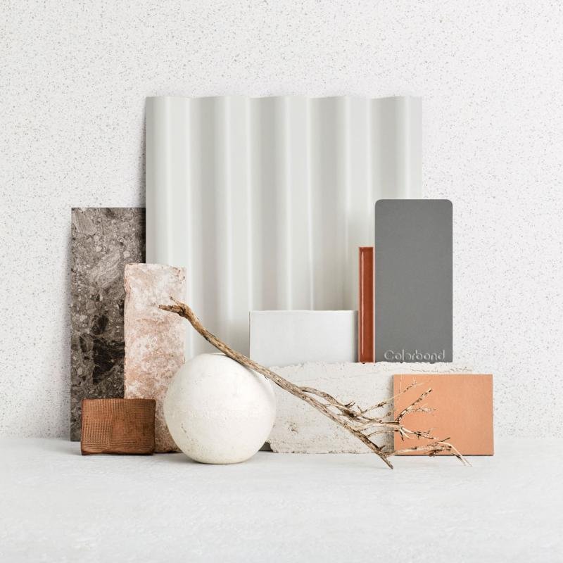 A collection of various textured tiles, a white ceramic vase, a dried branch, and color swatch cards arranged against a light background.