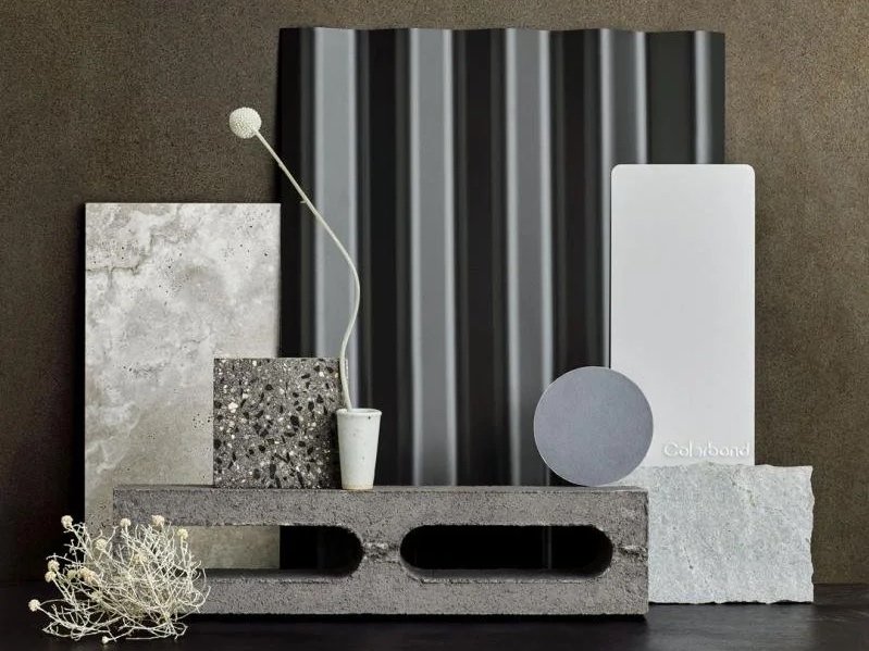 Display of interior design materials including tiles, a mural, and color samples arranged on a concrete block with a wall background.