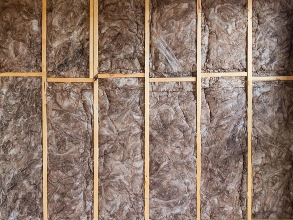 Interior wall with exposed wooden framing and brown insulation material.