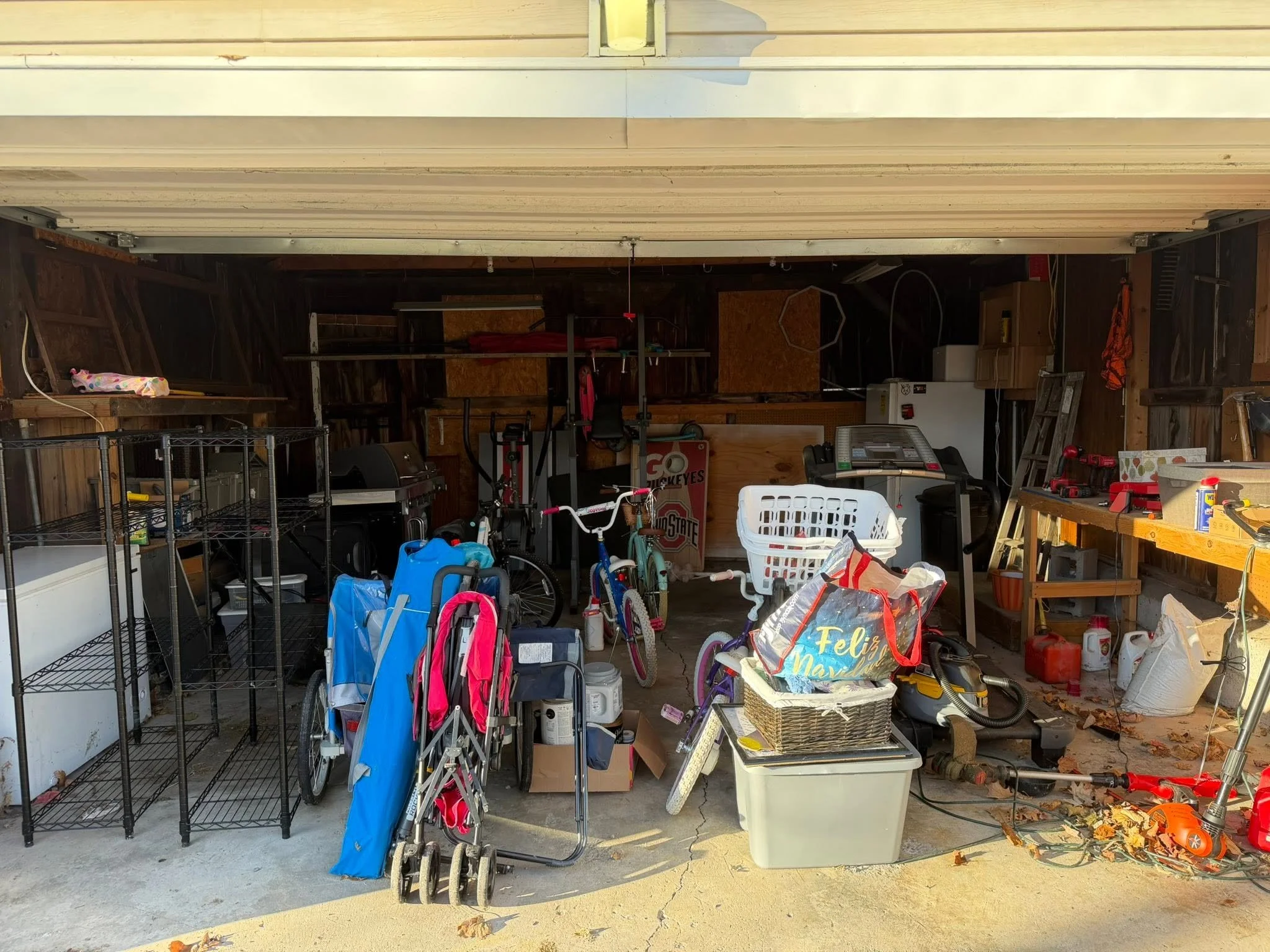 A cluttered garage filled with children's toys, bicycles, shelves, and various household items.