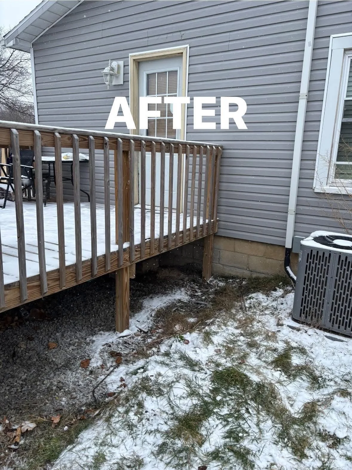 Backyard with a small wooden deck covered in snow, attached to a gray house with vinyl siding and a door. Snow and some grass are visible on the ground. An air conditioning unit is nearby.
