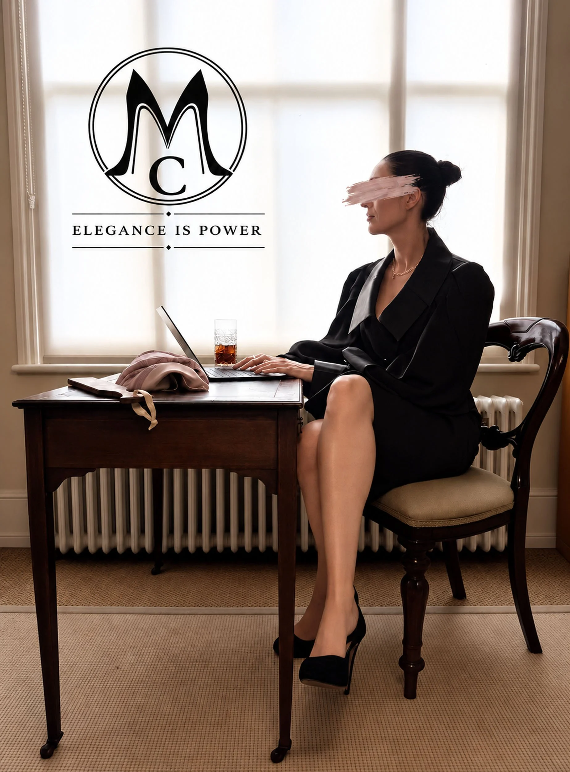 Mistress Coramina  sitting at a wooden table in front of a window. She is dressed in a beaultiful black satin blouse, lack fitted satin pencil skirt, wearing black high heels and a necklace. There is a laptop and a wooden paddle on the table