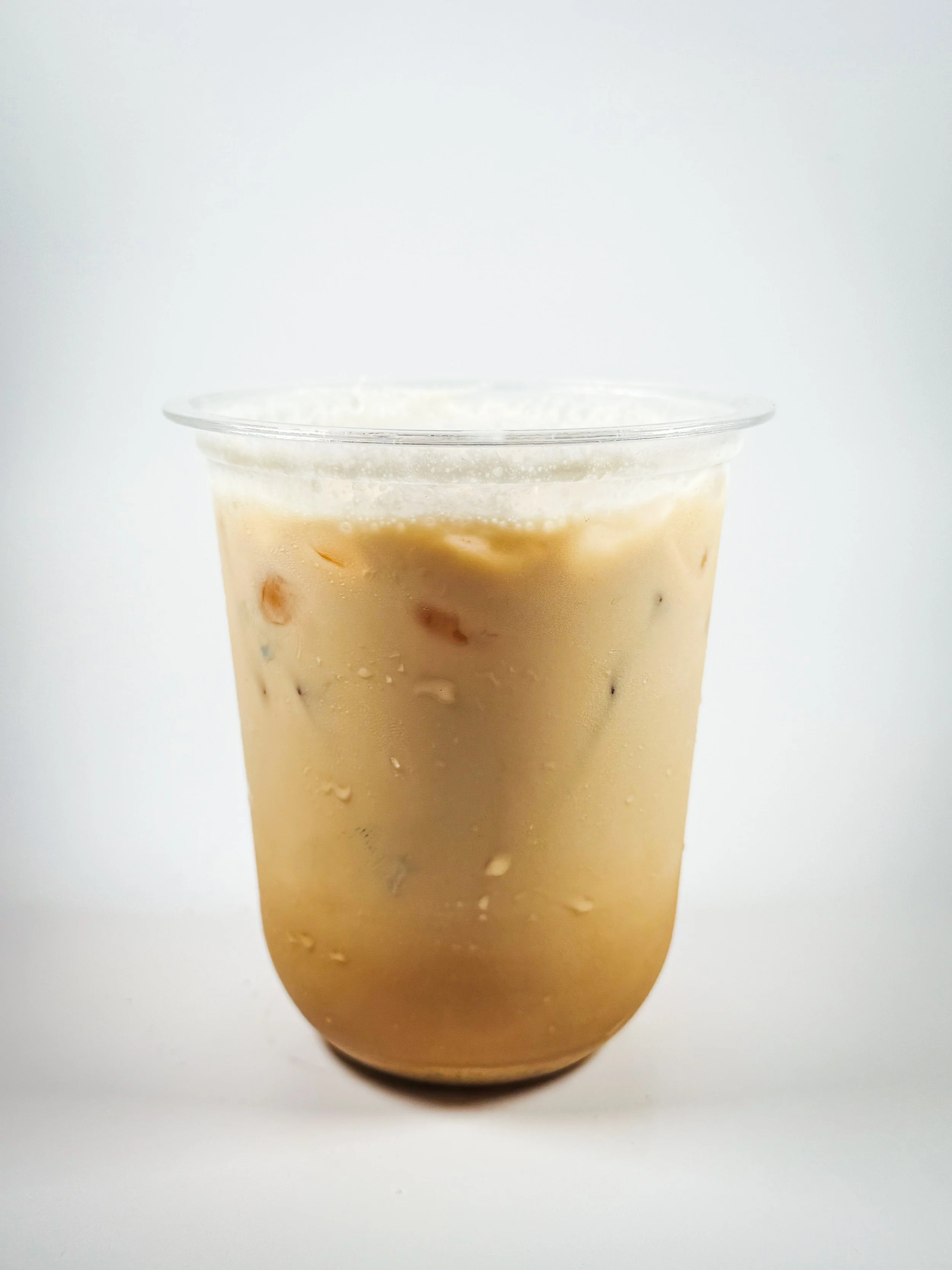A clear plastic cup filled with iced coffee or iced latte with visible ice cubes.
