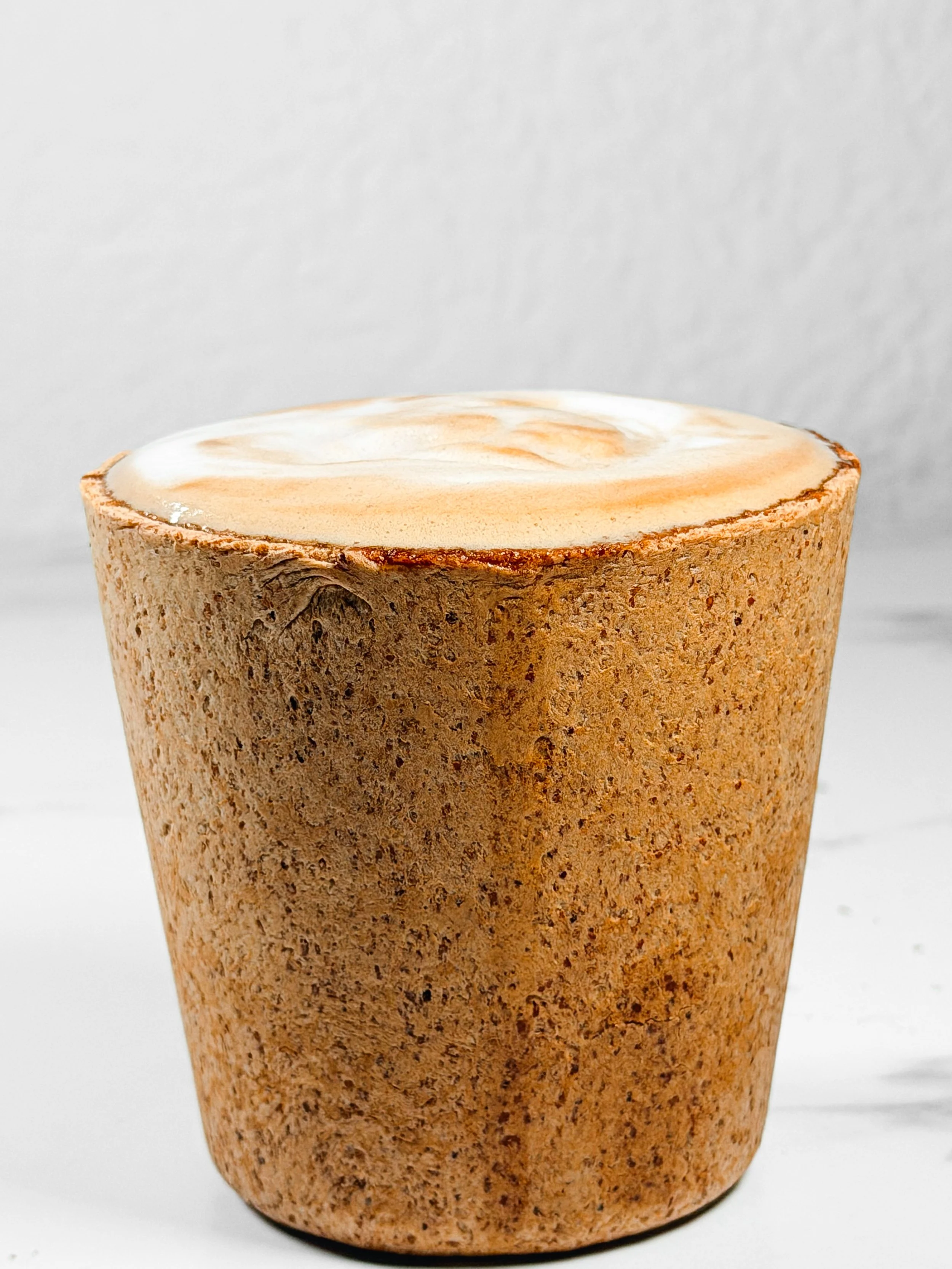 Close-up of a wooden cup with a smooth, polished surface and a visible wood grain pattern on a white background.