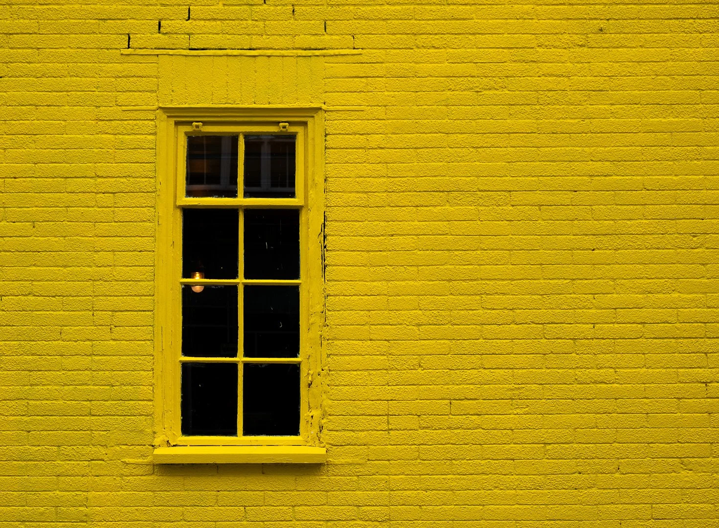 A yellow brick wall with a yellow-painted window frame.
