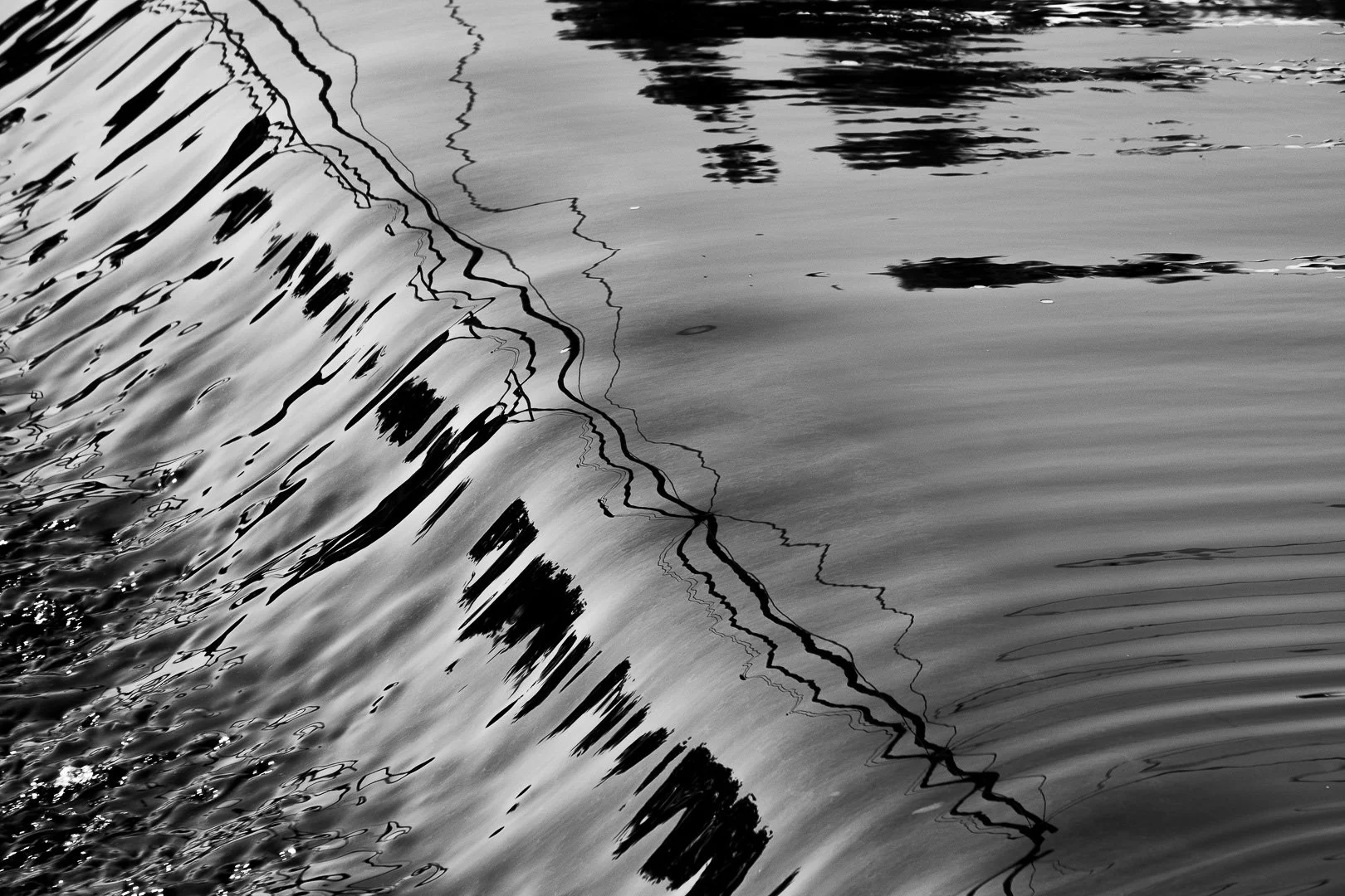 Close-up of water with reflections and surface ripples, black and white photo.