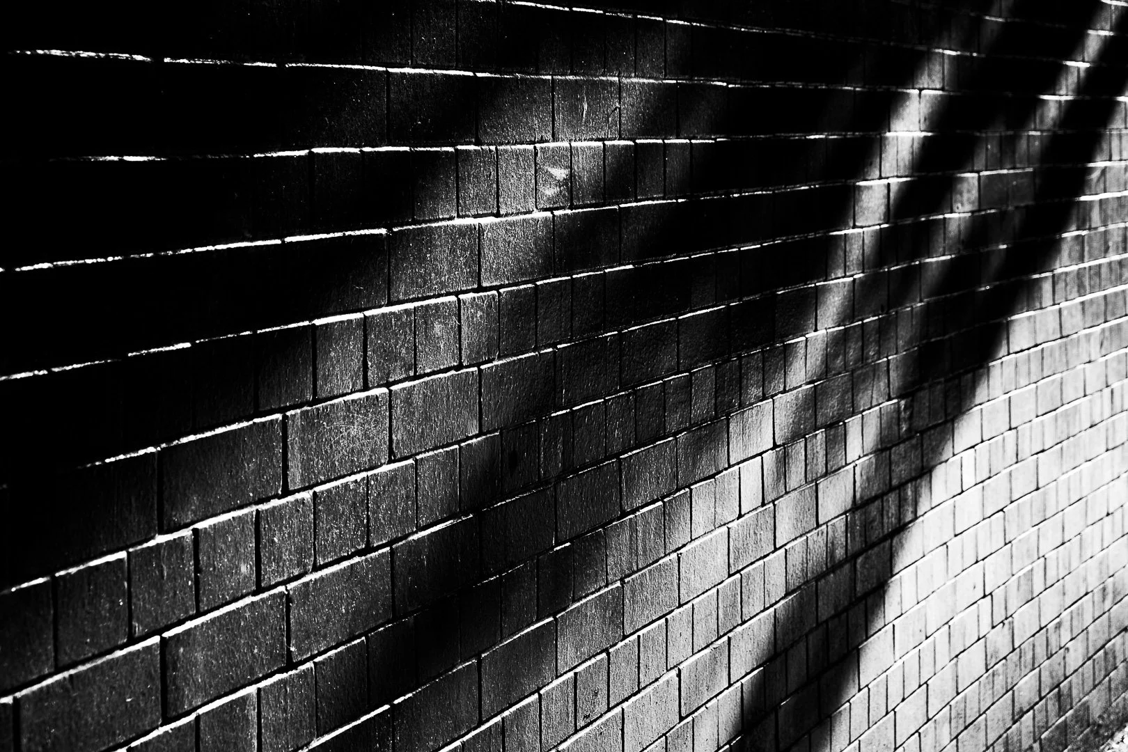 Black brick wall with shadow cast across it.