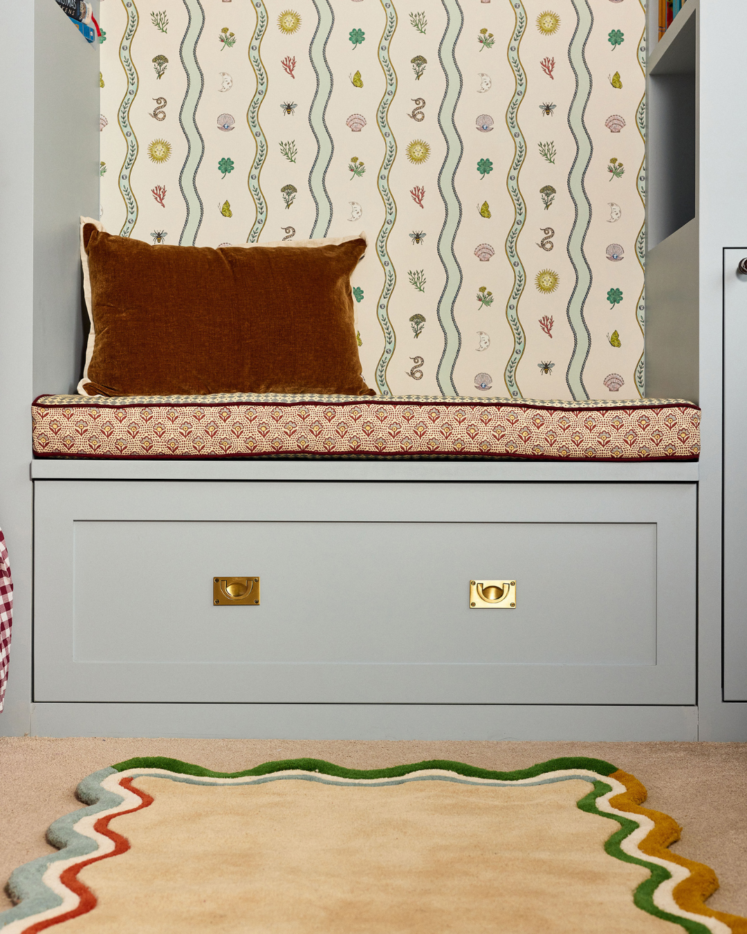 children room in light blue muted tones. with burgundy accents and wave patterns. close up reading nook bench and storage