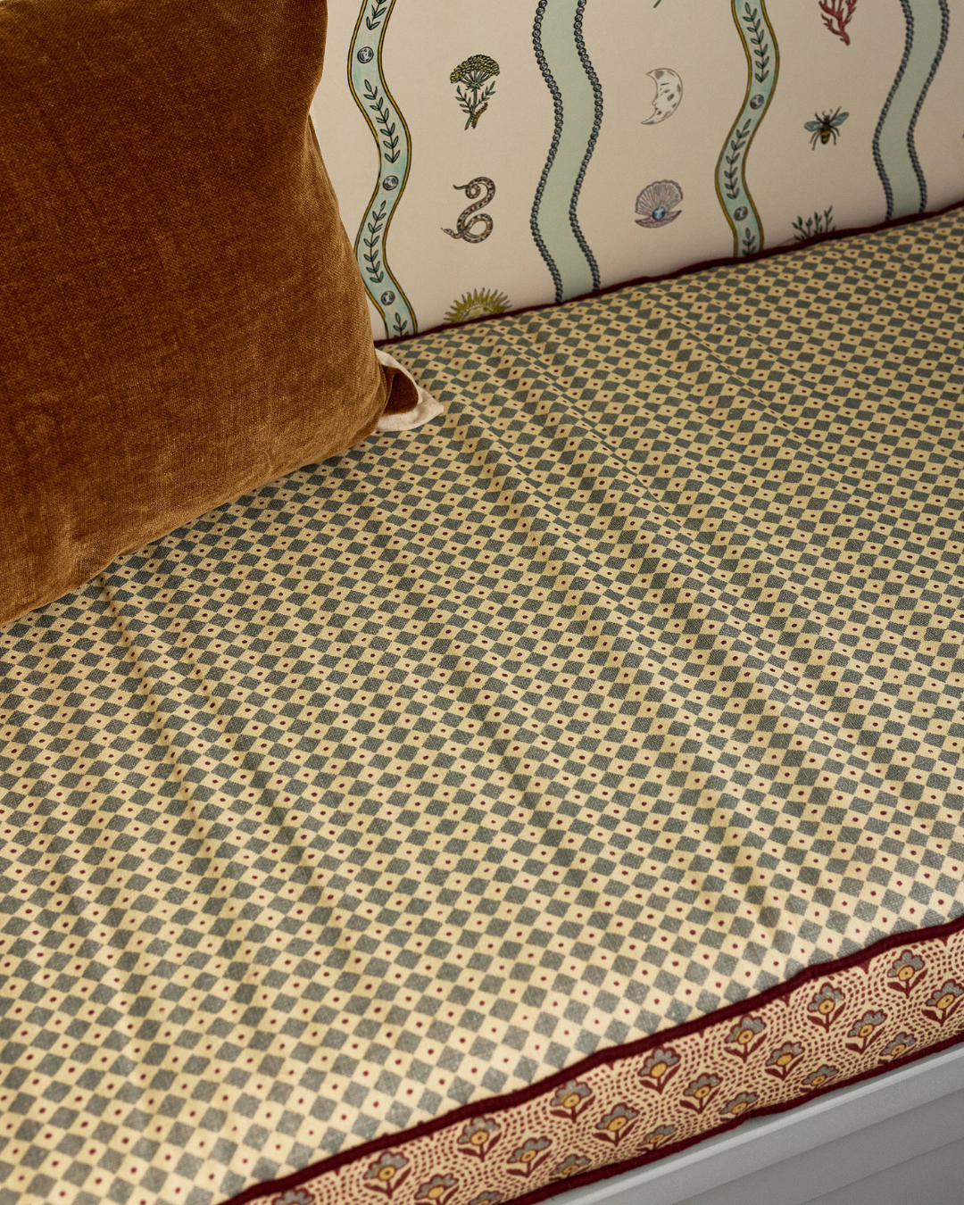 children room in light blue muted tones. with burgundy accents and wave patterns. close up bench cushion