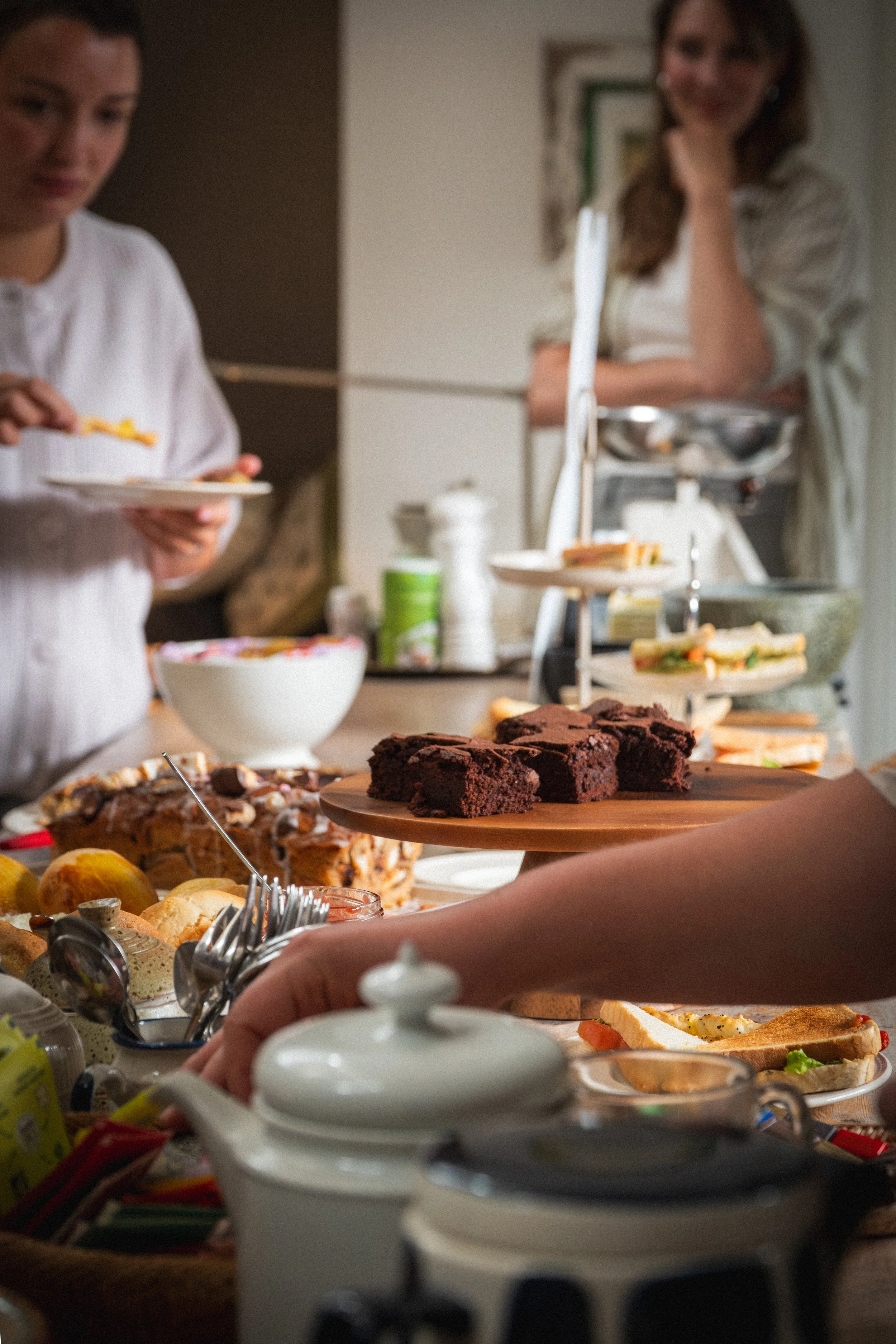 Mensen die genieten van een buffet met verschillende desserts, taarten en sandwiches, klaar om te serveren.