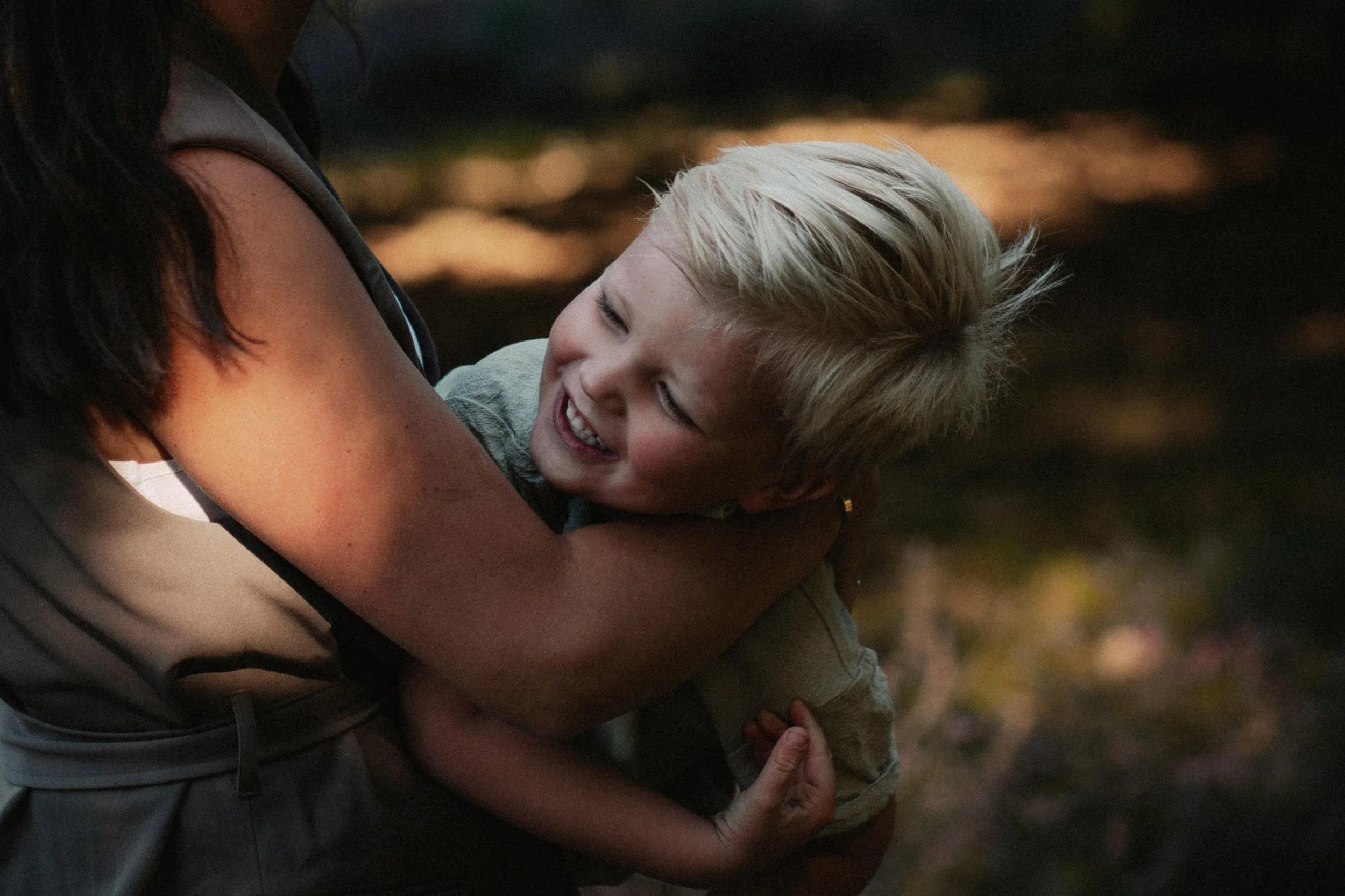Een jongen in de armen van een vrouw, ze lachen en hebben plezier samen.