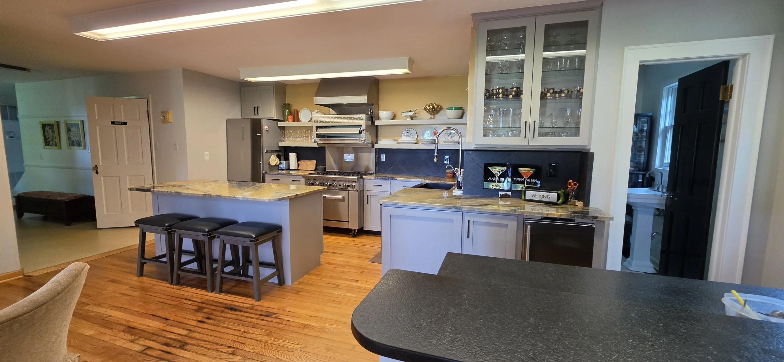 Kitchen with granite countertops, stainless steel appliances, white cabinets, glass-front display cabinets, and hardwood flooring.