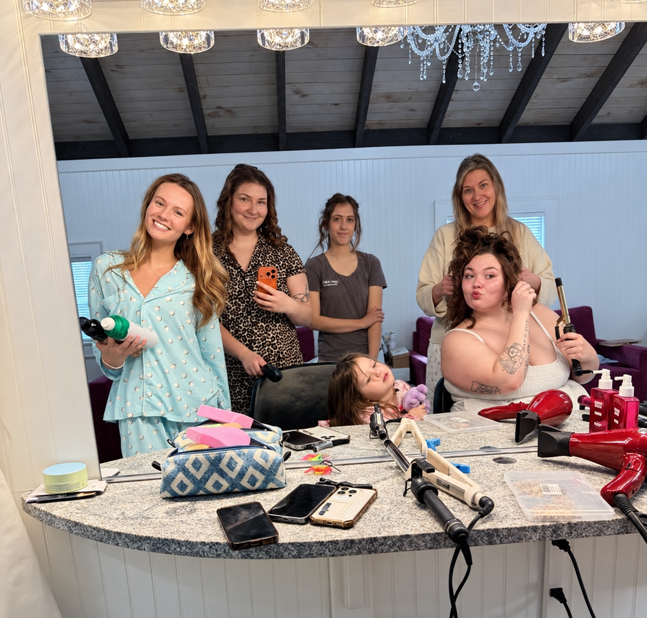 Bride and wedding party getting ready together in the bridal studio at Bostwick’s Magnolia Manor, reflected in a large mirror.