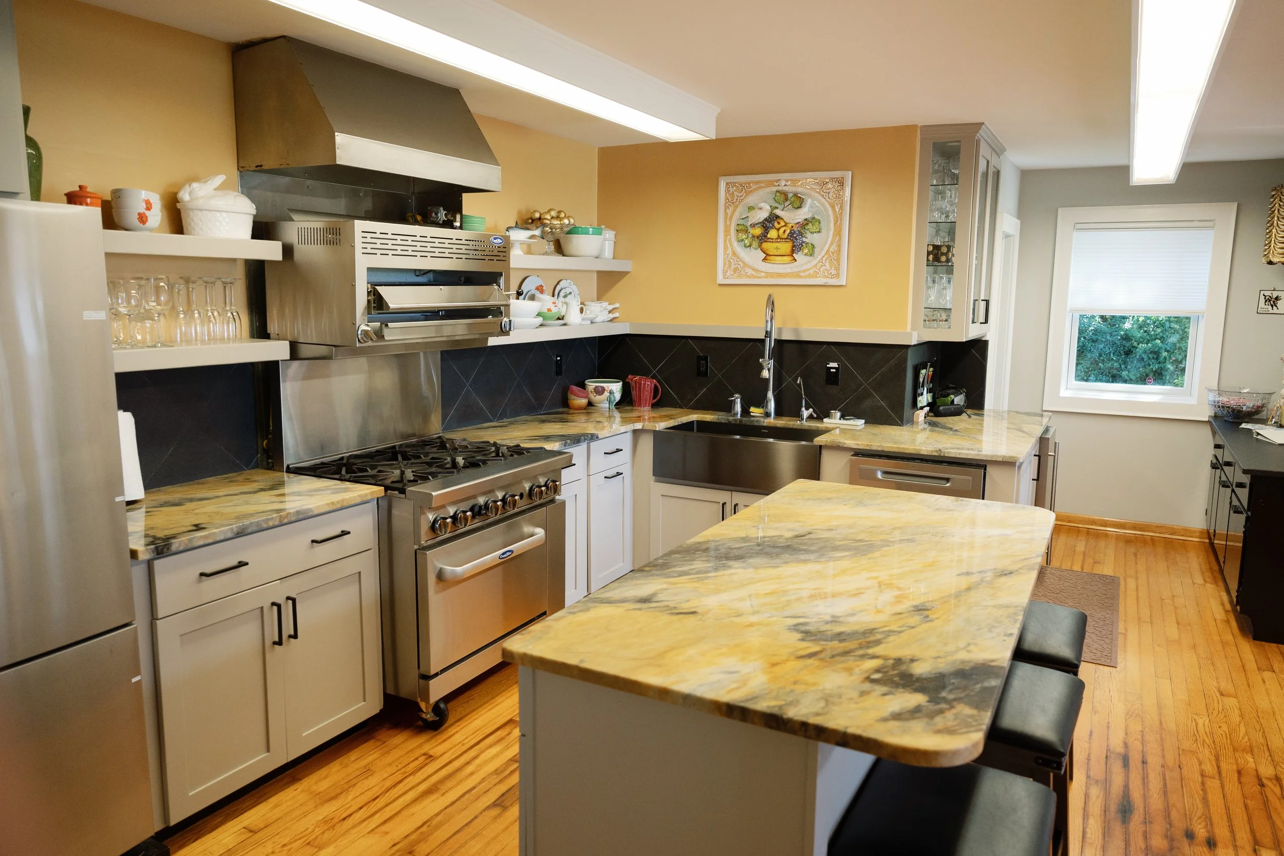 Spacious traditional kitchen with a large island, granite countertops, stainless steel range, sink, cabinets, and hardwood floors