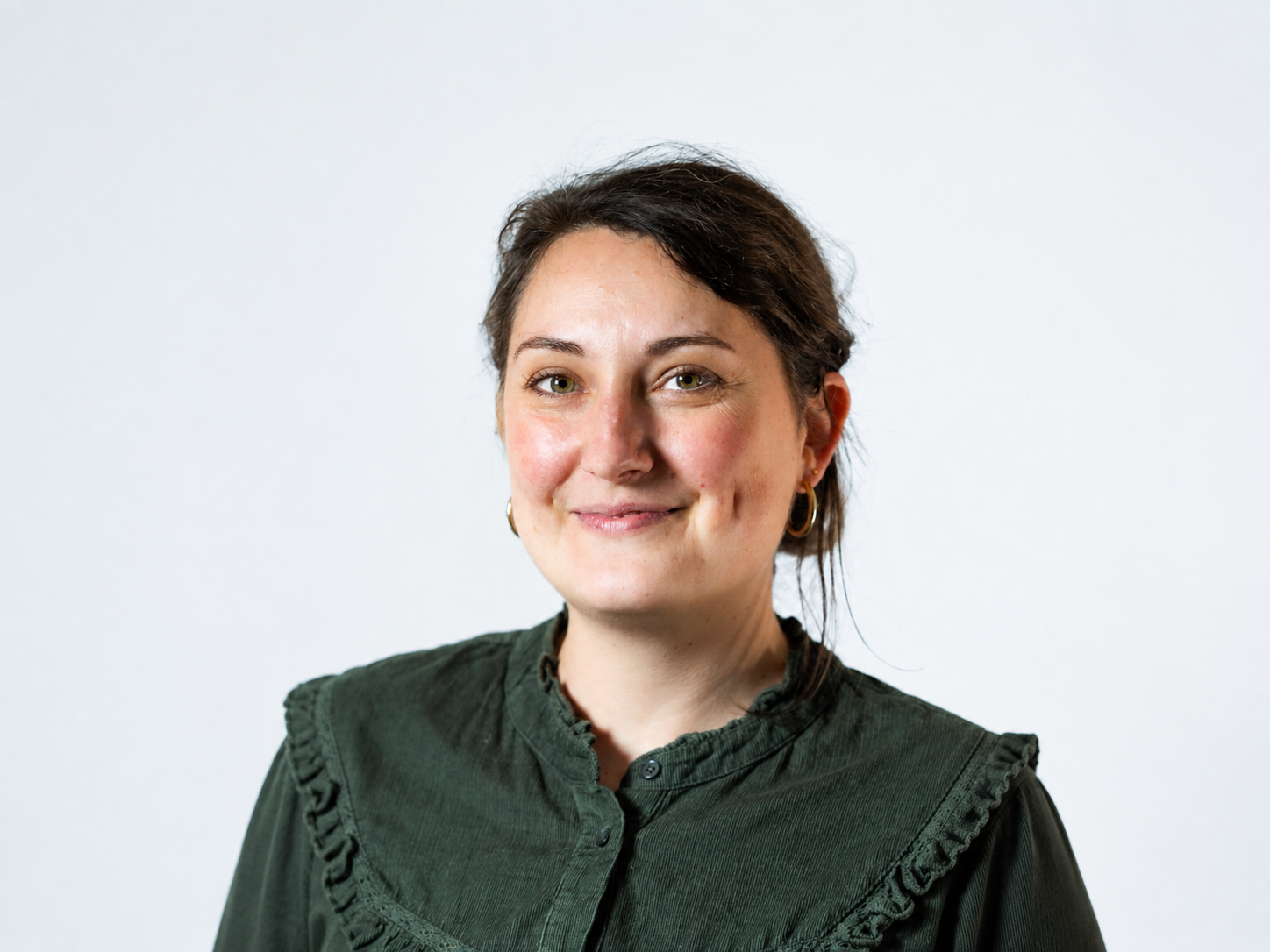 Georgia Blondet - Une femme souriante avec des cheveux courts bruns, portant un haut vert foncé.