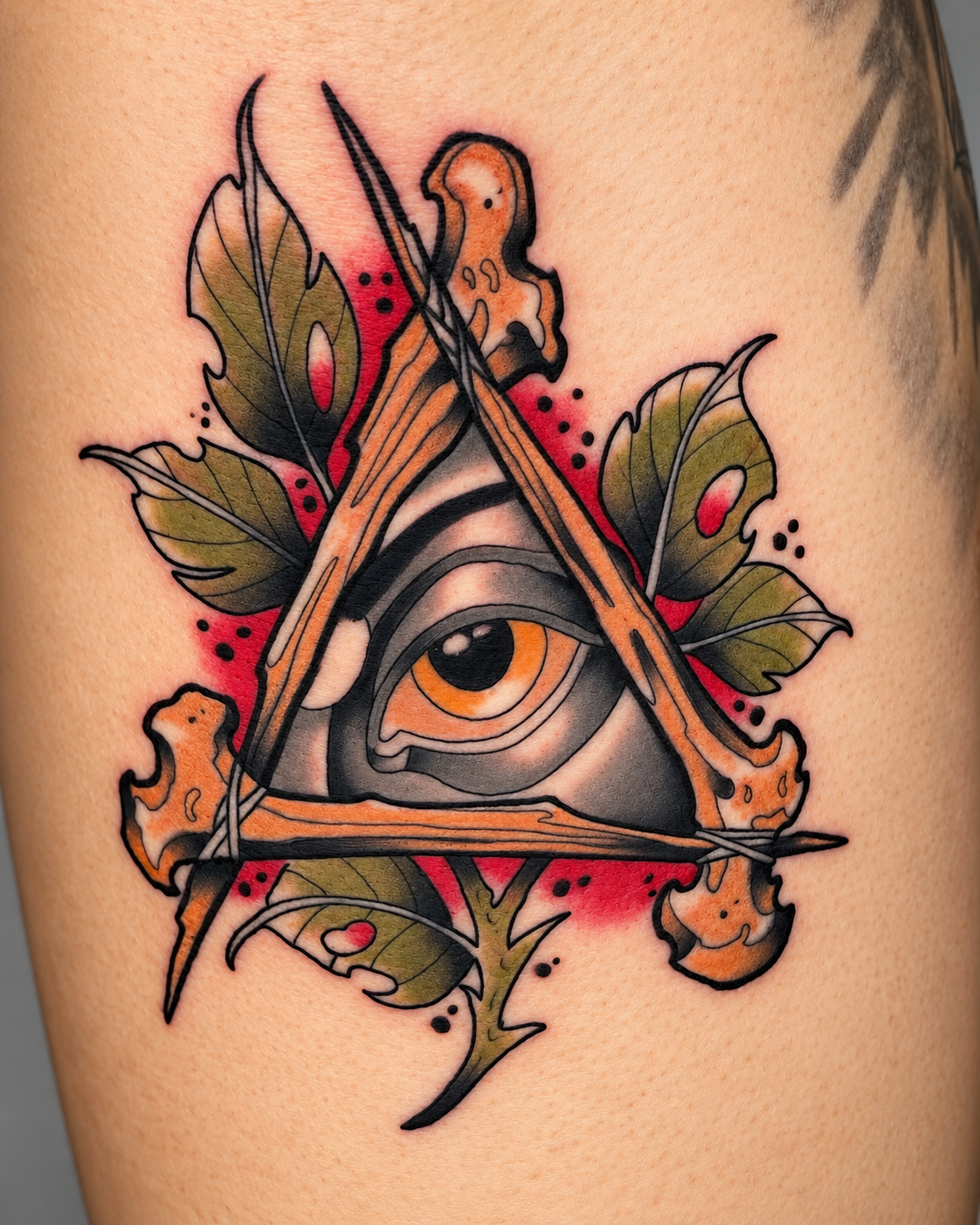All-seeing eye tattoo with triangle, leaves, and red accents by Miami tattoo artist Adrian Aguirre