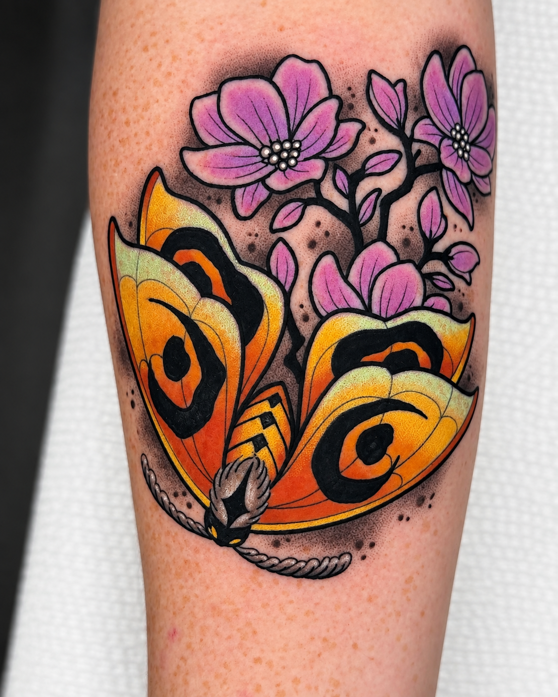 Yellow butterfly tattoo with pink flowers on the arm, by Miami tattoo artist Adrian Aguirre.