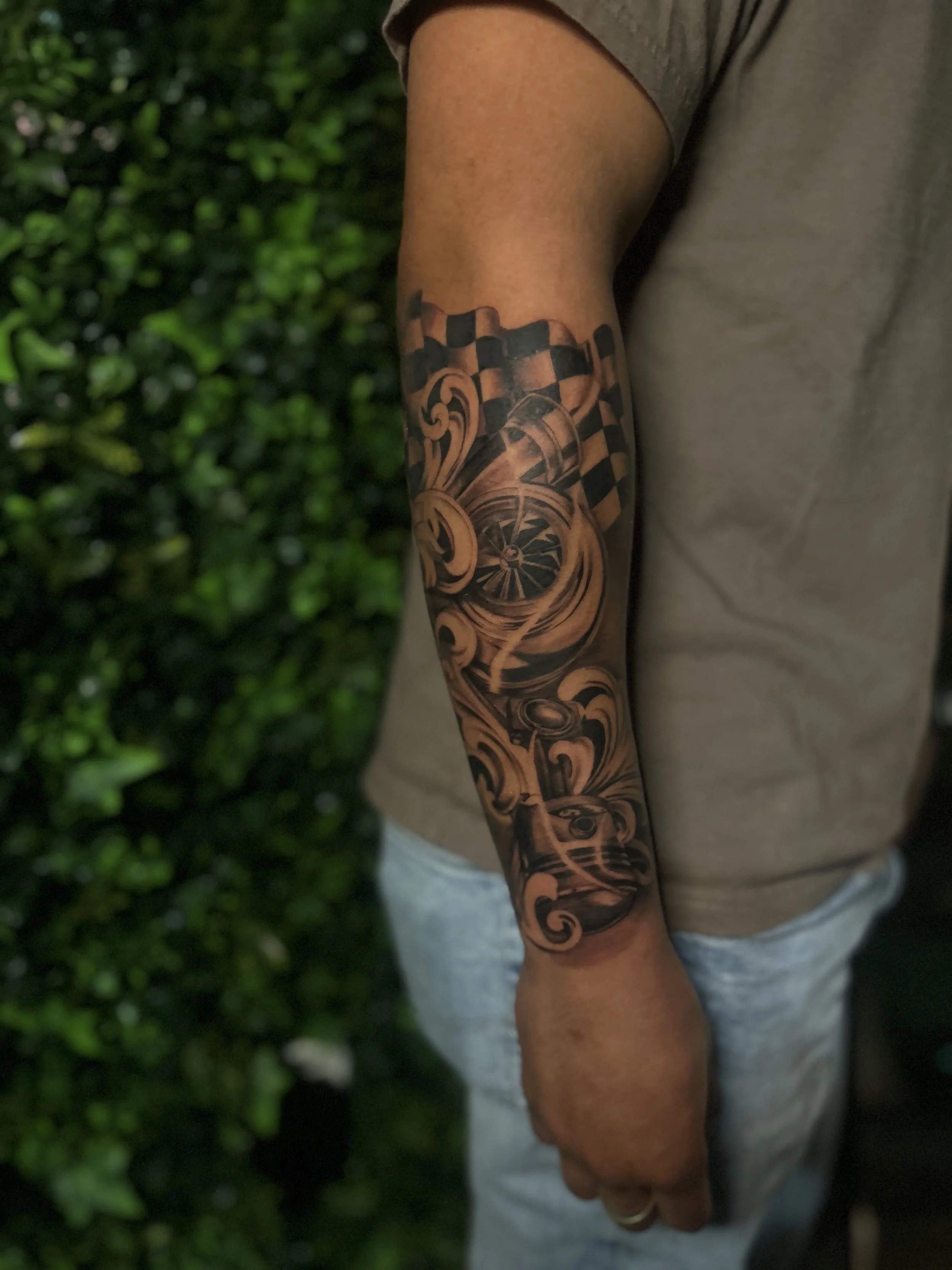 A tattoo of a spinning wheel and checkered pattern on a person's forearm.