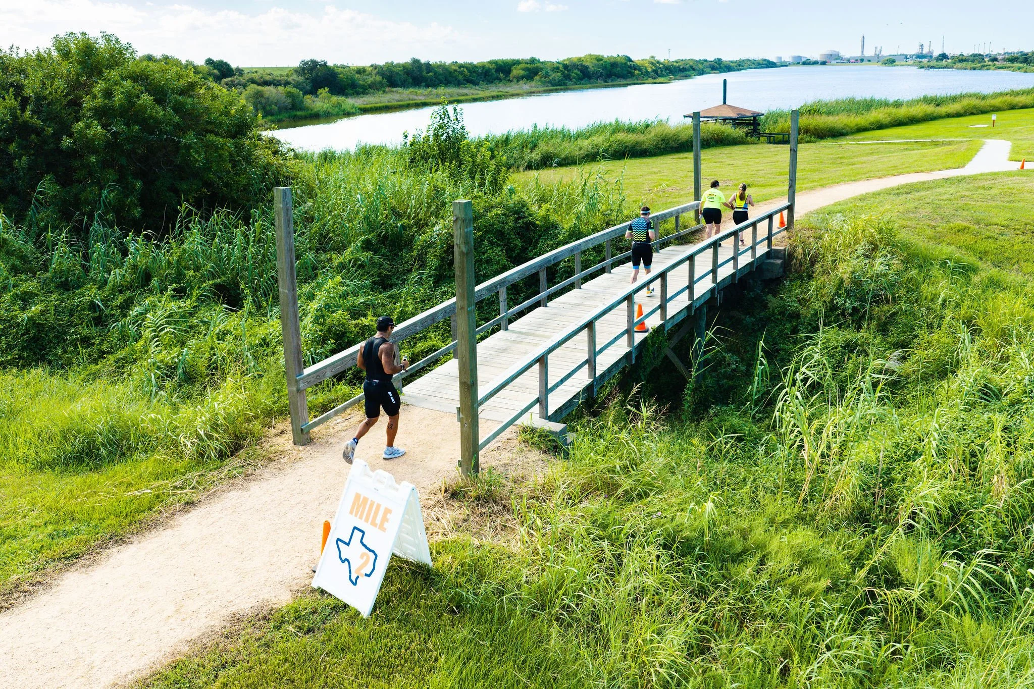 Runners crossing a park bridge