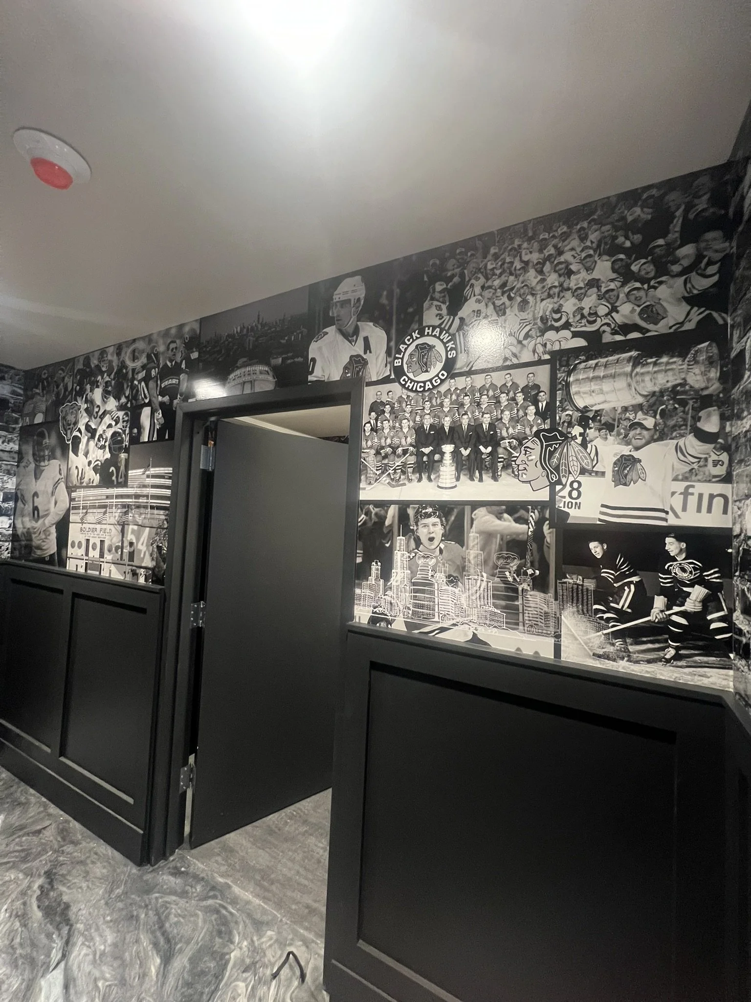Black and white collage of hockey players and team photos on a wall, including a Chicago Blackhawks logo.