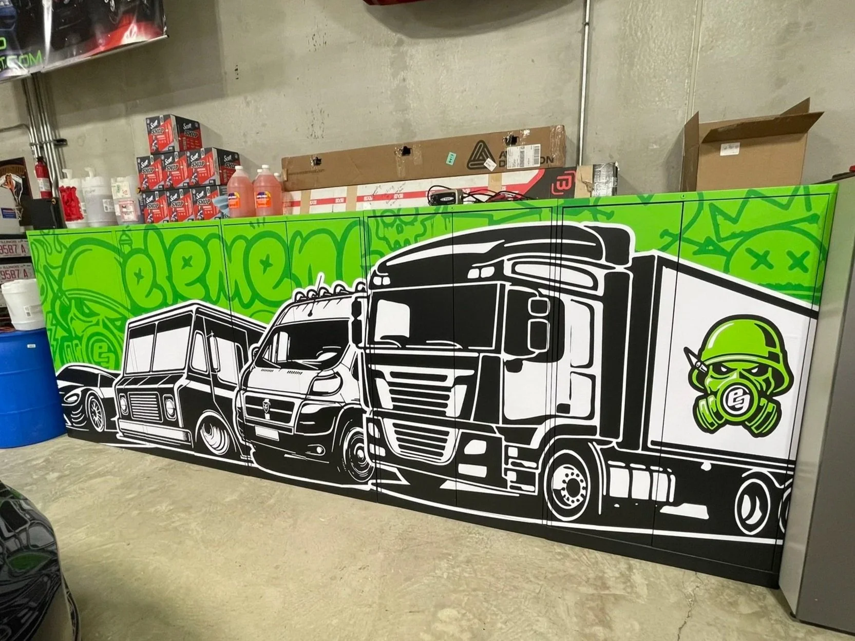 Green and black custom wrap with illustrated trucks and vans on cabinets inside the Element Graphics shop