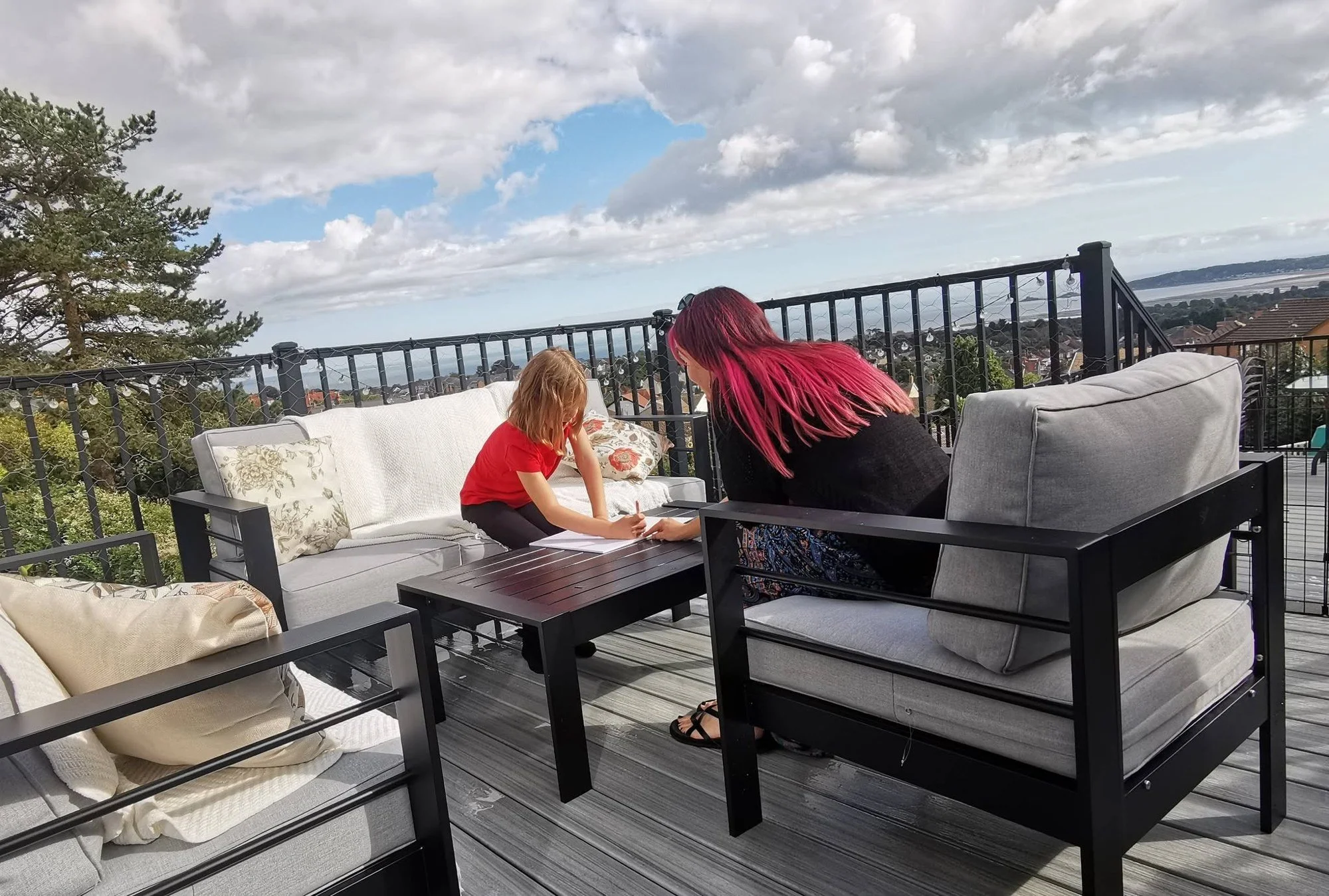Sarah helping a child with written work at an outdoor table