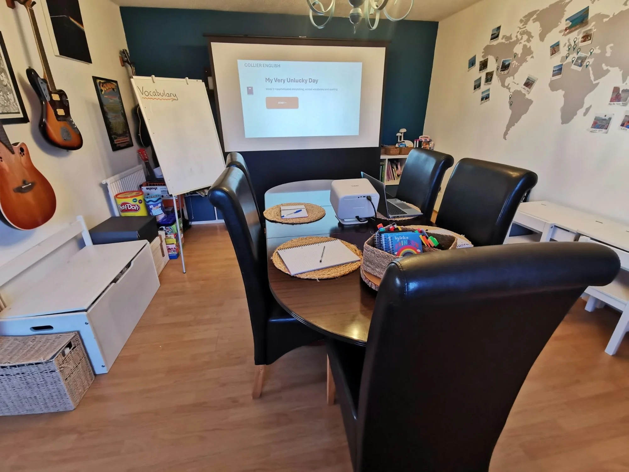 Teaching room set up for English lessons, with a round table, chairs and a projector screen