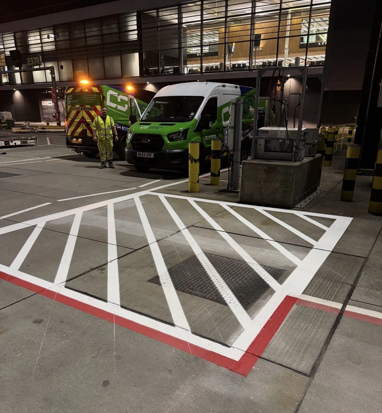Maintenance vans and a worker in high-visibility clothing at an airport service bay