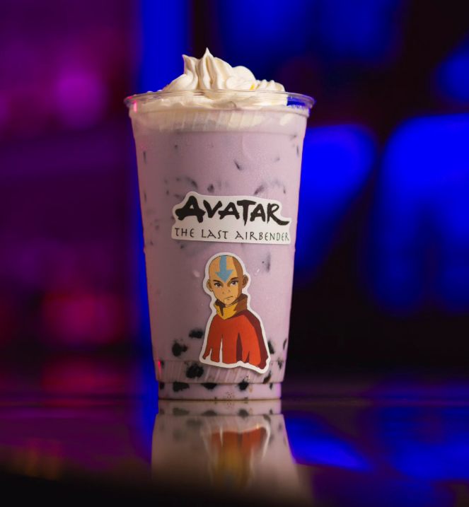 A tall glass of purple bubble tea with black tapioca pearls at the bottom, topped with whipped cream, and decorated with an Avatar movie sticker featuring the character Princess Yue.