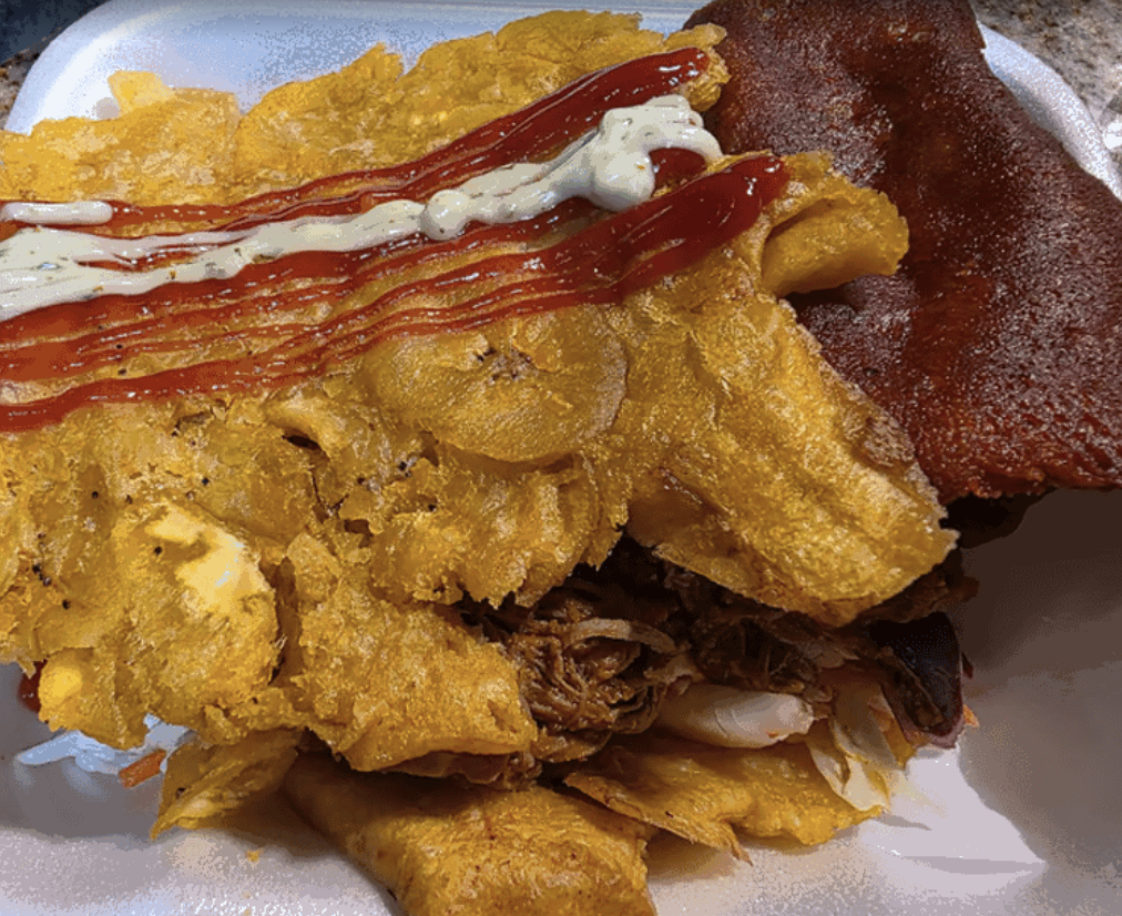 Close-up of a plate with fried chicken topped with ketchup and mayonnaise, and a side of fried fish fillet.