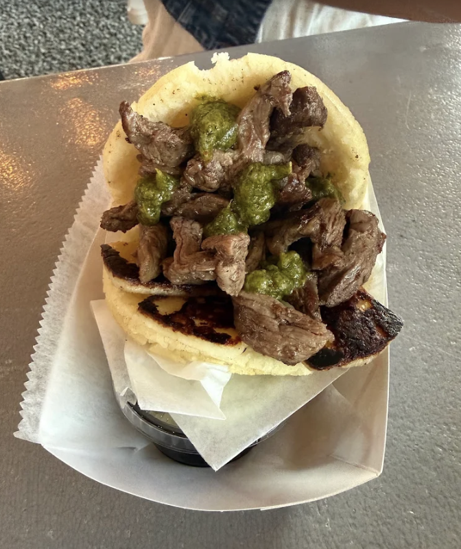 Beef taco with chopped grilled beef and green salsa, served on a corn tortilla in a paper boat