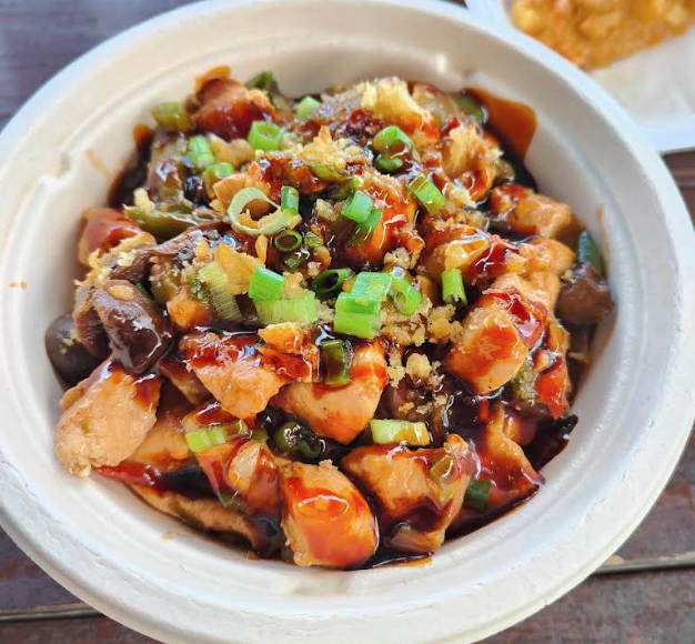 Chinese chicken and vegetable stir-fry with green onions served in a white disposable bowl.