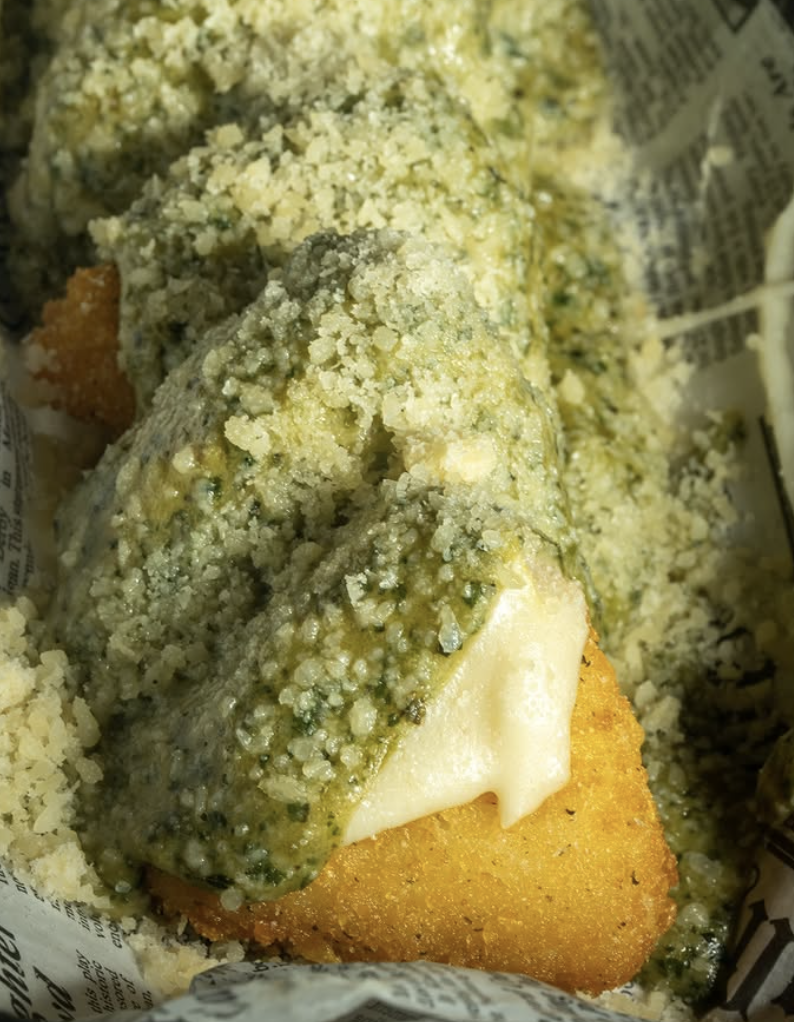 Fried fish fillet topped with tartar sauce, served on a bed of crushed crackers or breadcrumbs.