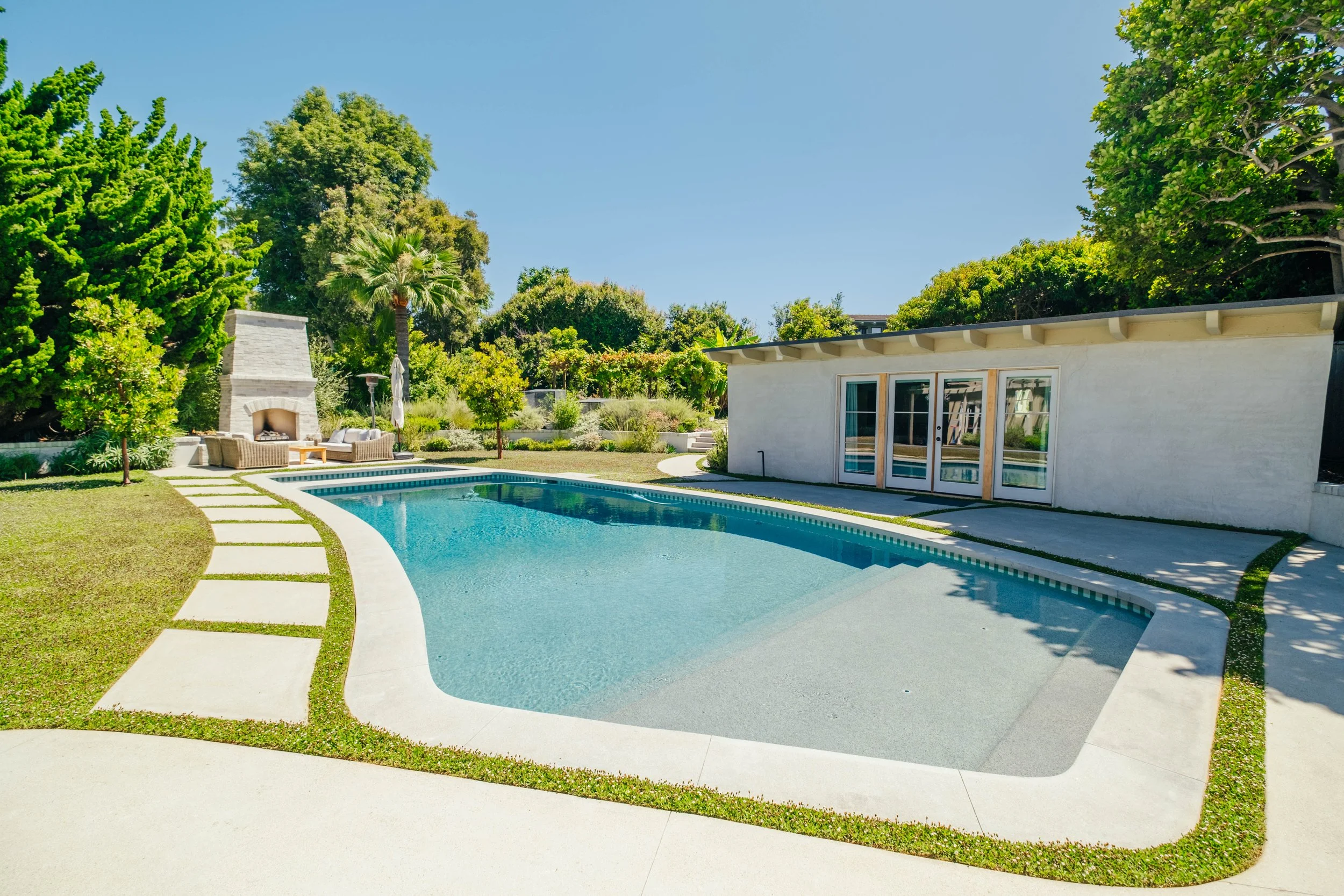 Custom backyard swimming pool with surrounding landscaping by Rosewood Landscape