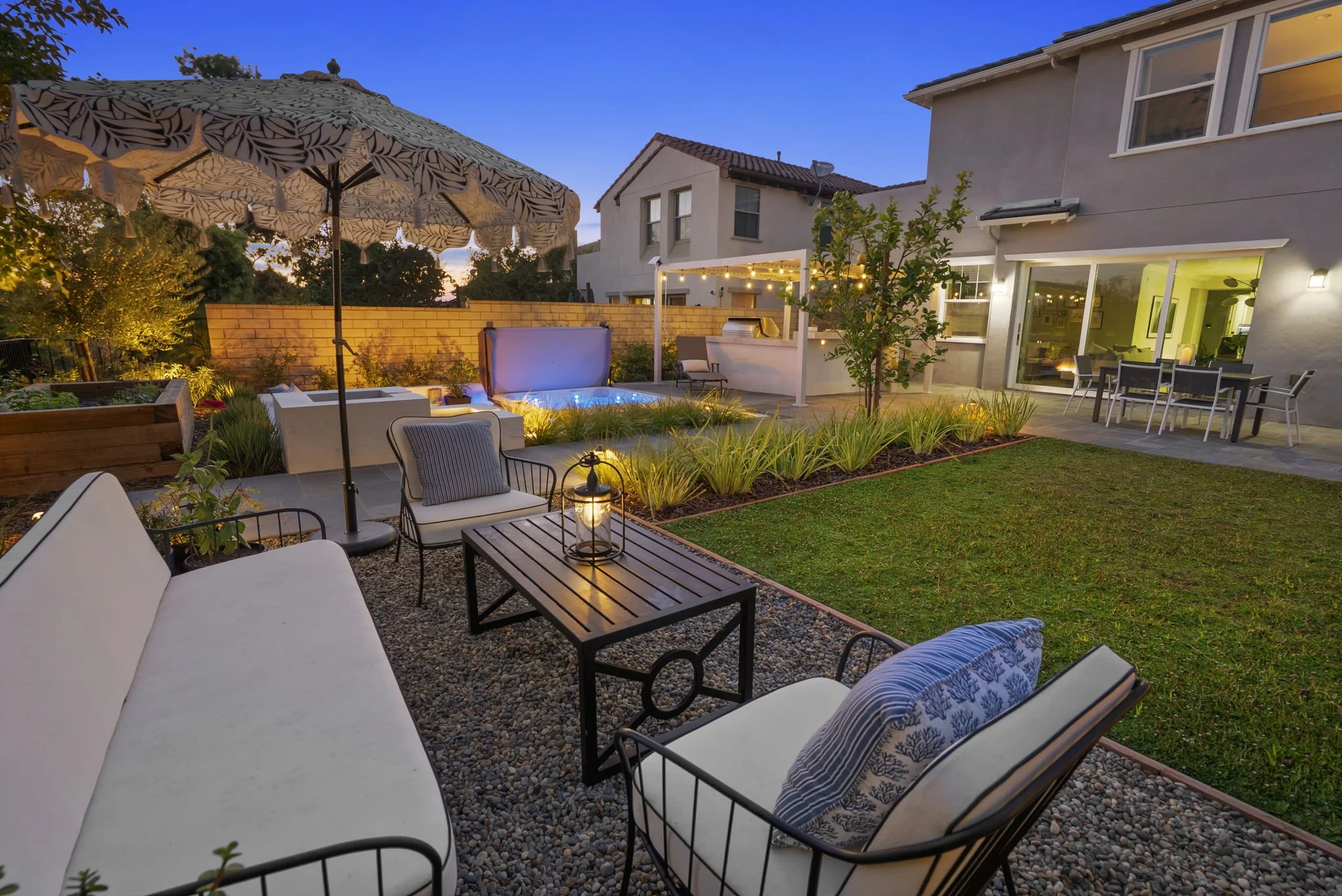 Backyard outdoor living space with patio seating, lawn, spa and landscape lighting by Rosewood Landscape