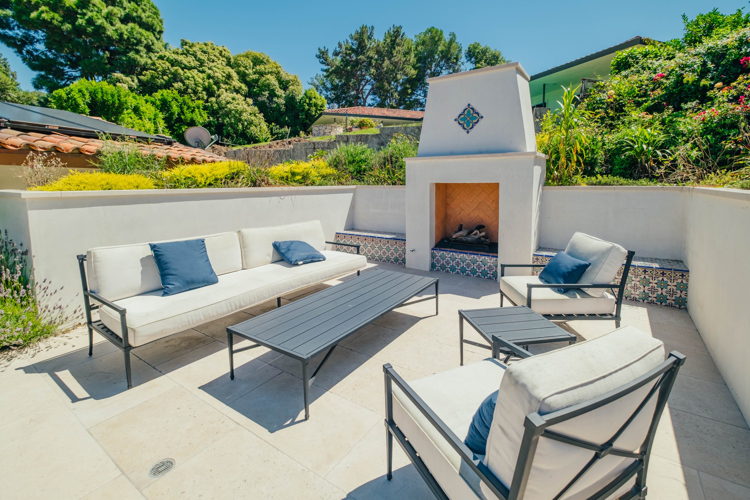 Custom outdoor fireplace with patio seating and built-in tile benches by Rosewood Landscape