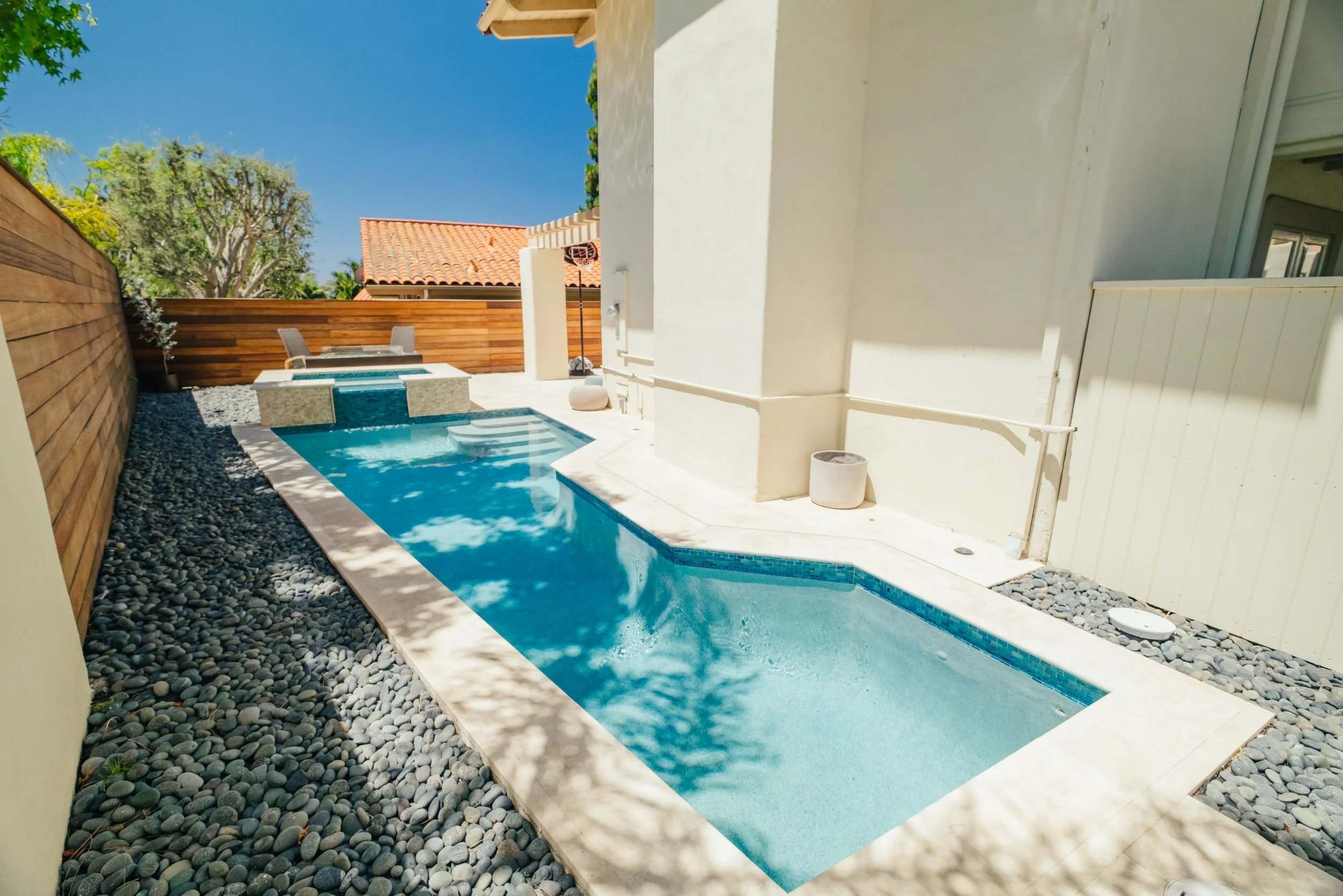 Custom swimming pool and spa integrated into a landscaped backyard by Rosewood Landscape