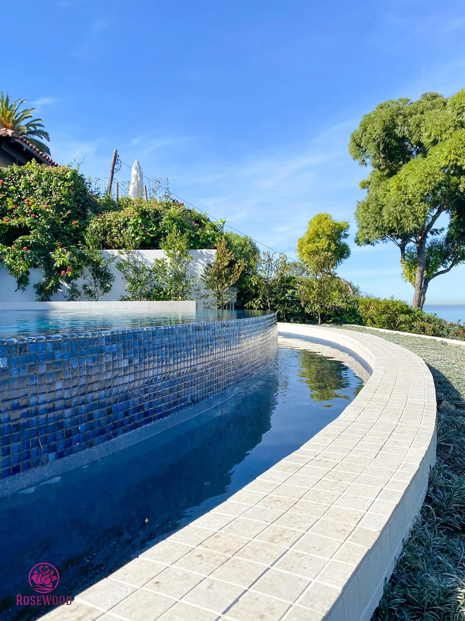 Custom infinity pool with tiled water feature by Rosewood Landscape