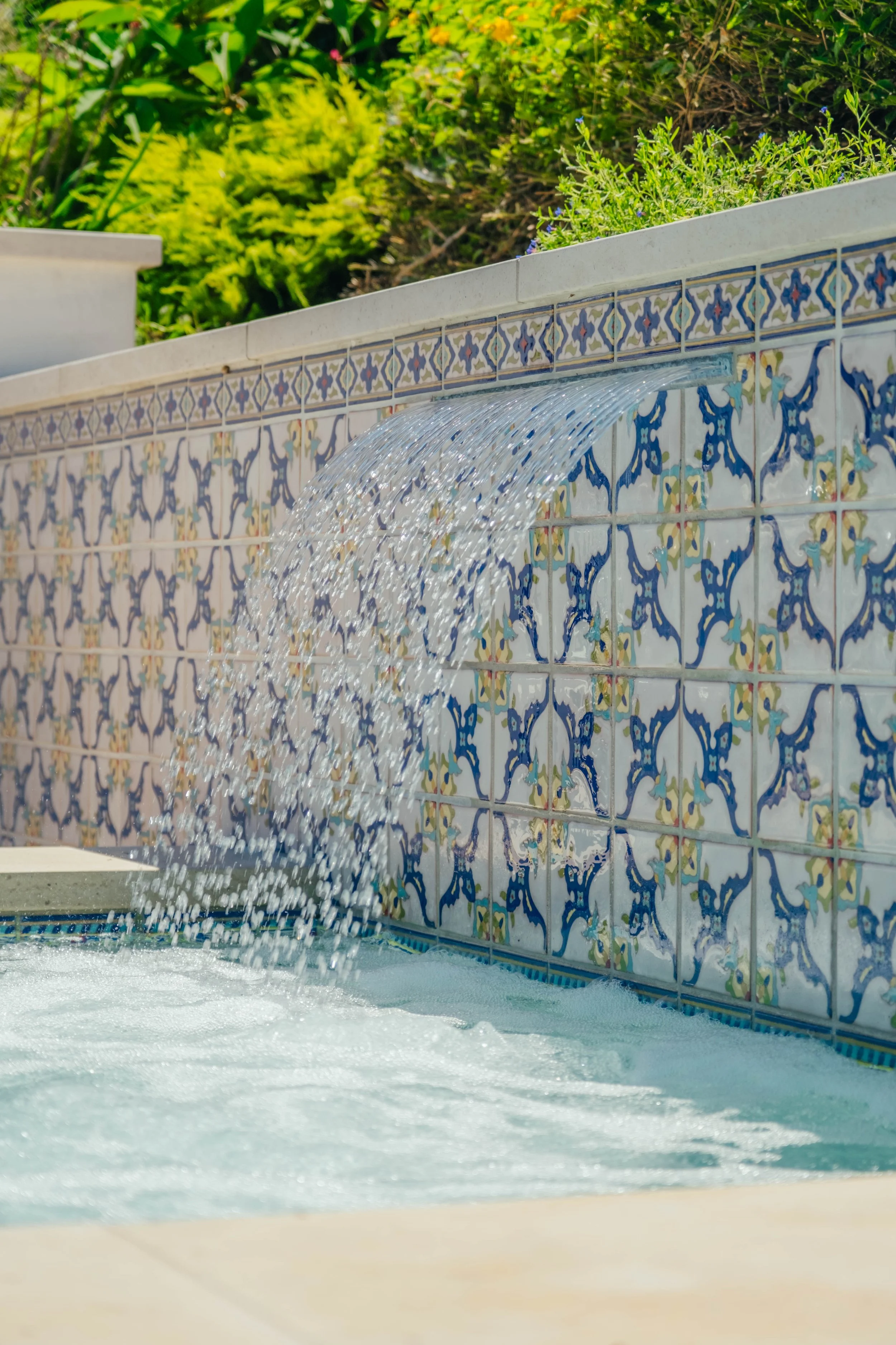 Custom spa with decorative tile and cascading water feature by Rosewood Landscape