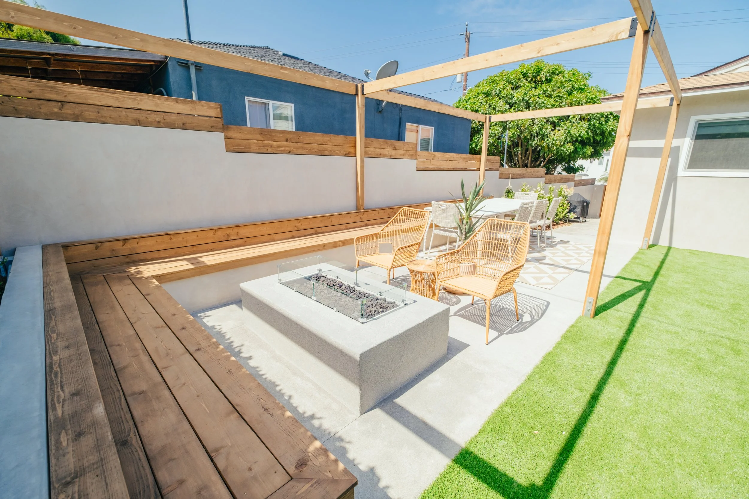 Custom hardscape patio with built-in seating and fire pit by Rosewood Landscape