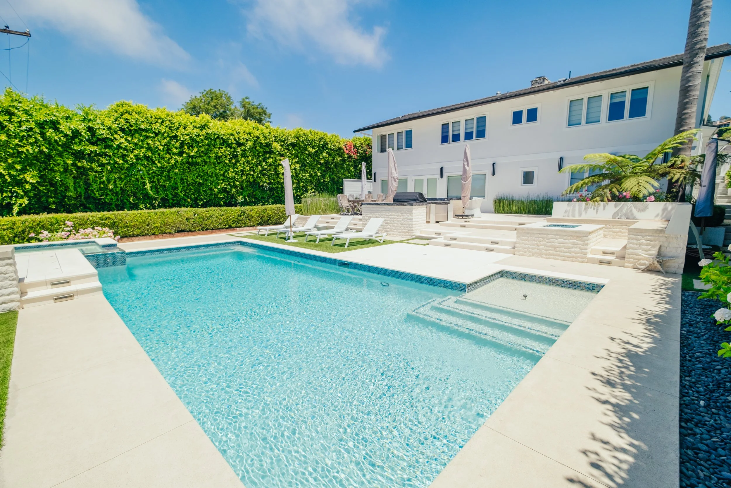 Luxury backyard swimming pool and spa with surrounding outdoor living space by Rosewood Landscape