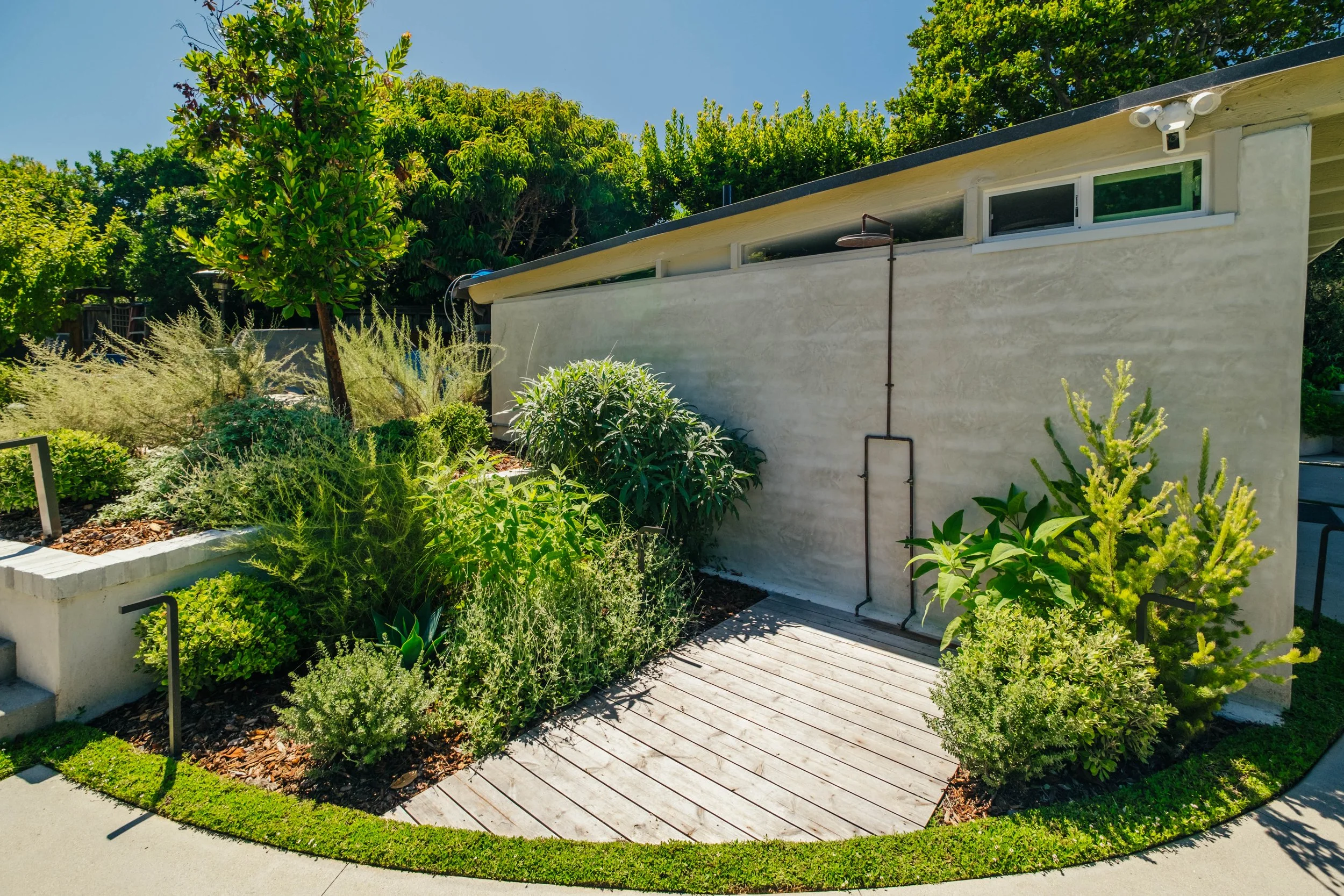 Outdoor shower surrounded by garden landscaping and greenery by Rosewood Landscape