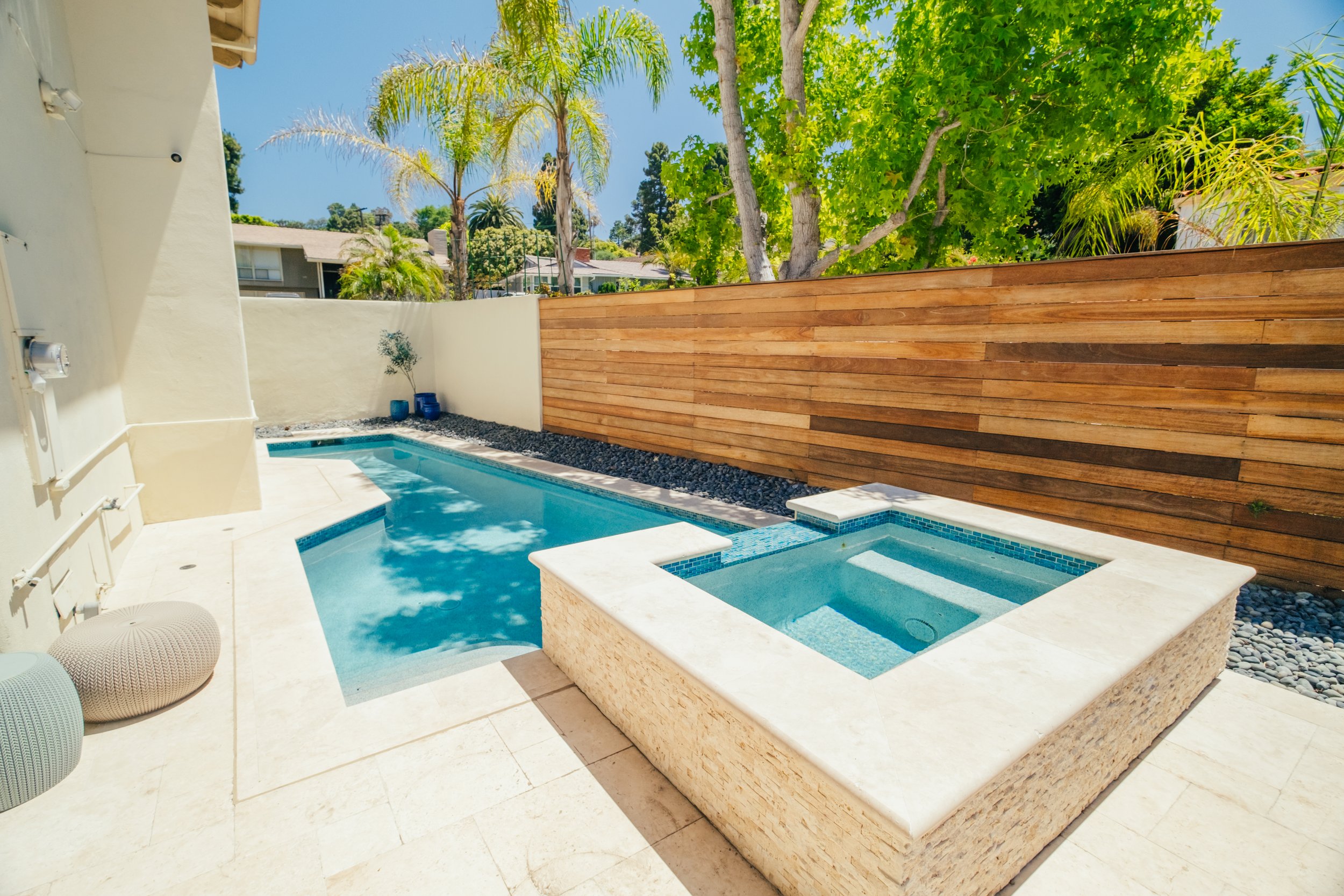 Custom backyard swimming pool with raised spa and surrounding hardscape by Rosewood Landscape