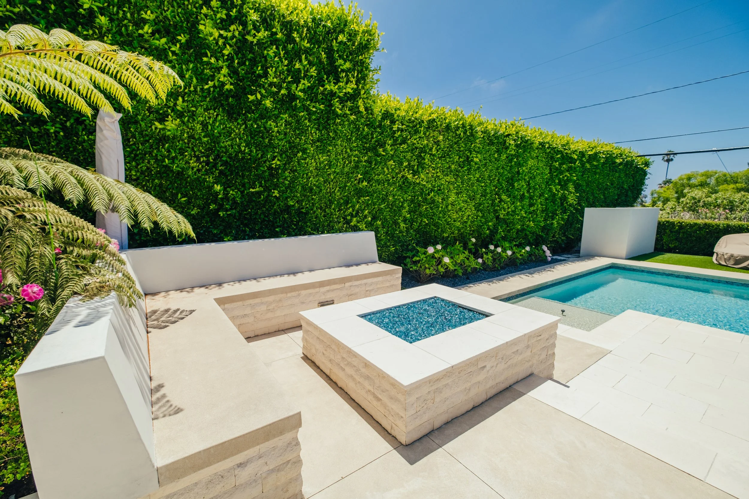Poolside fire pit with built-in outdoor seating by Rosewood Landscape